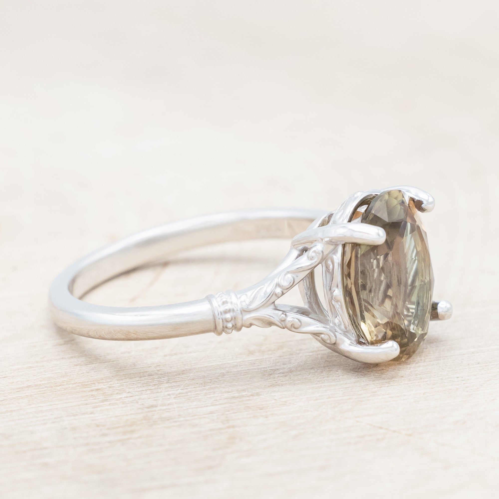 White gold ring with a sunstone on a wooden surface