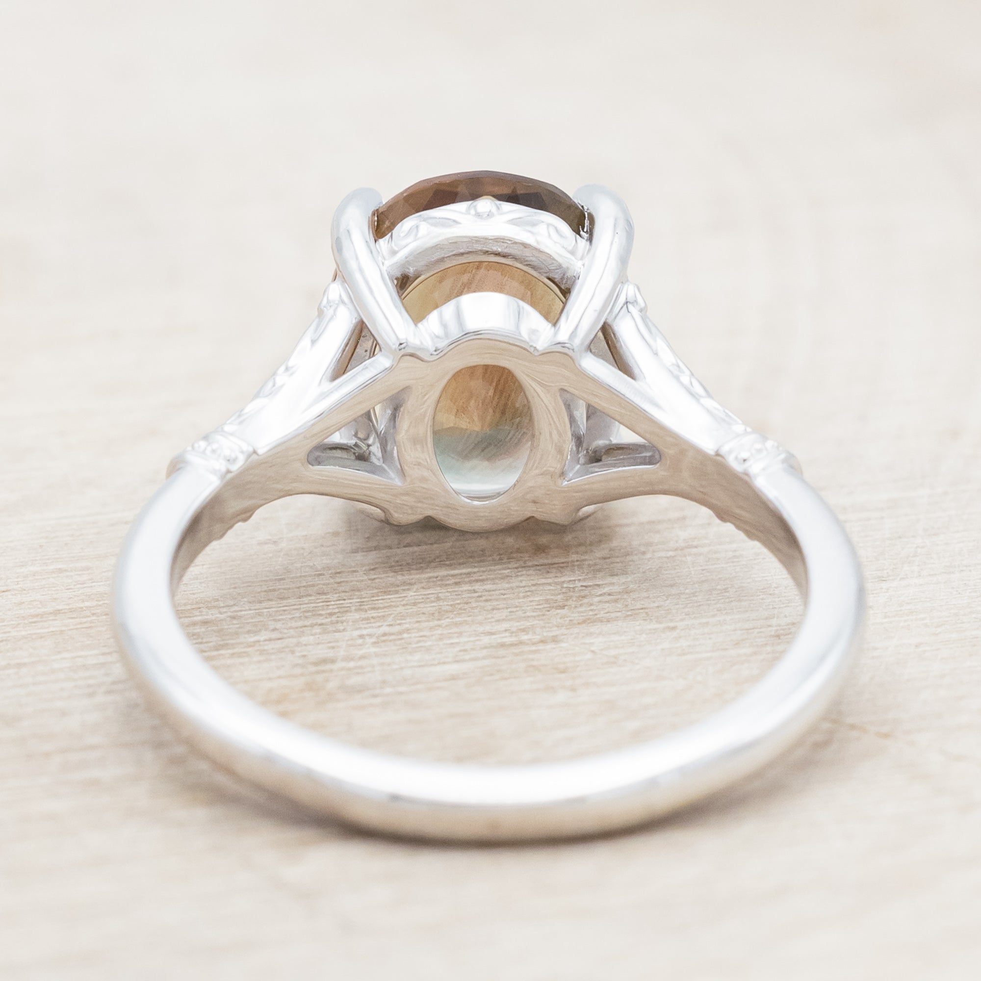 White gold ring with a sunstone on a wooden surface