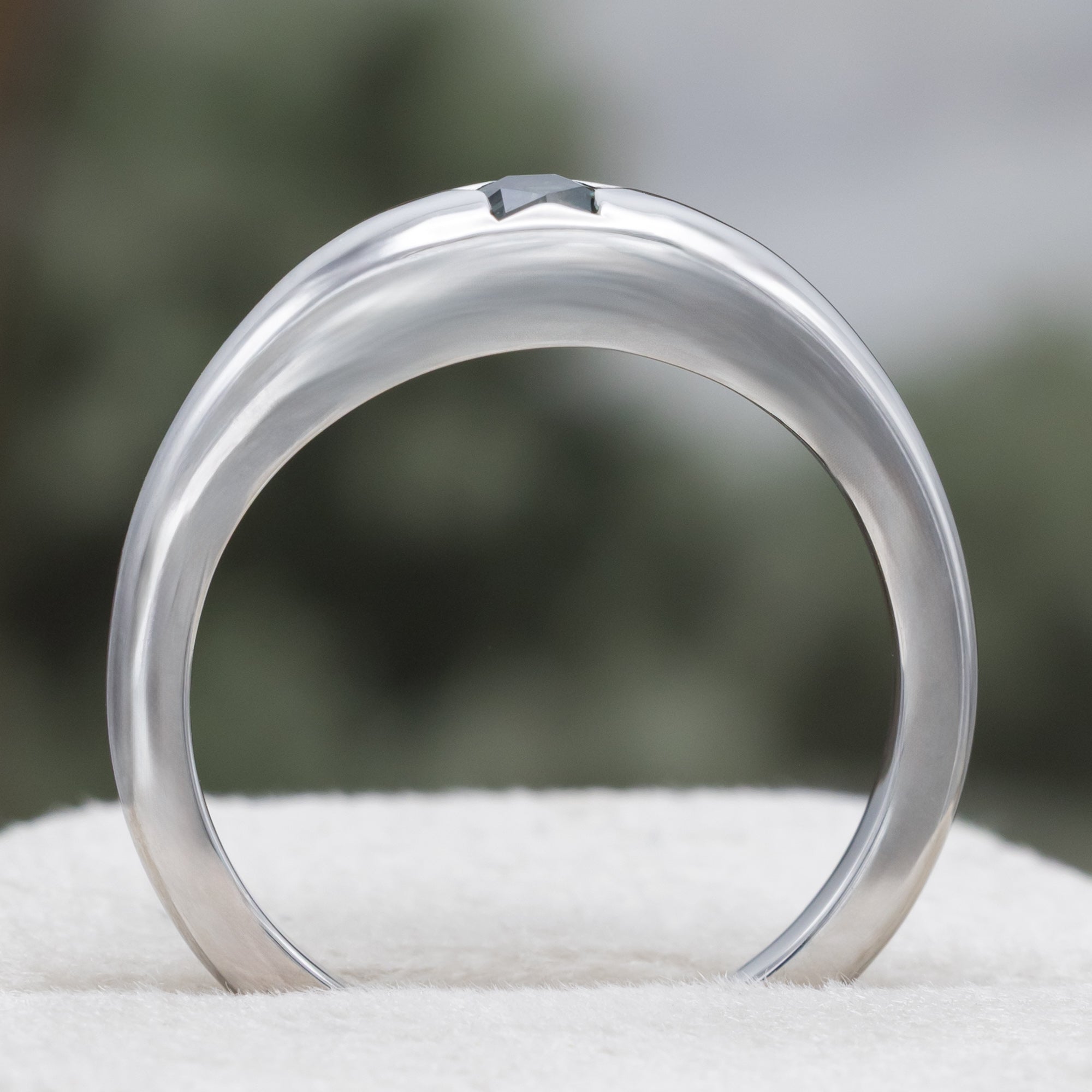 White gold ring with star shaped sapphire against a blurred green background