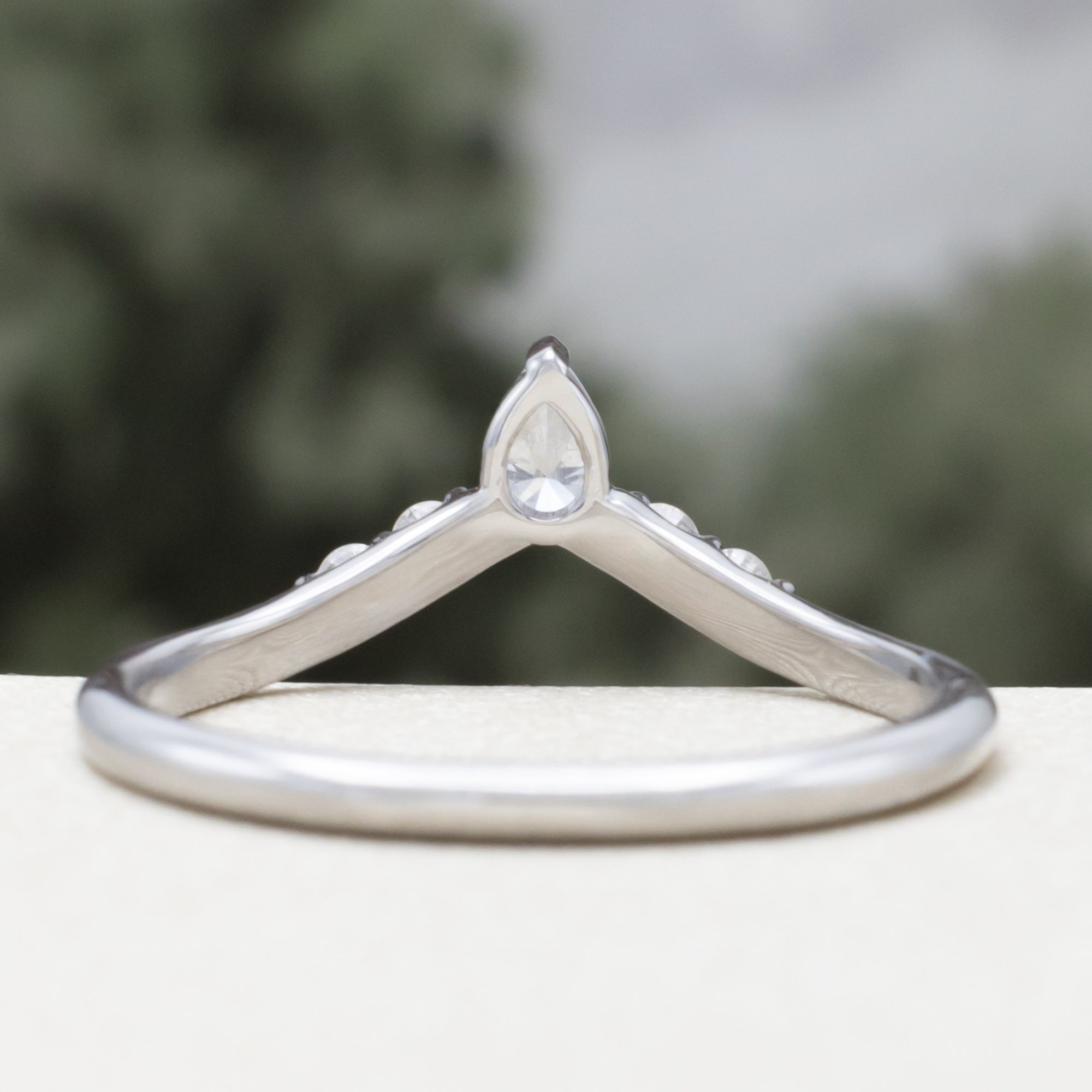 White gold ring with diamond accents on a blurred natural background