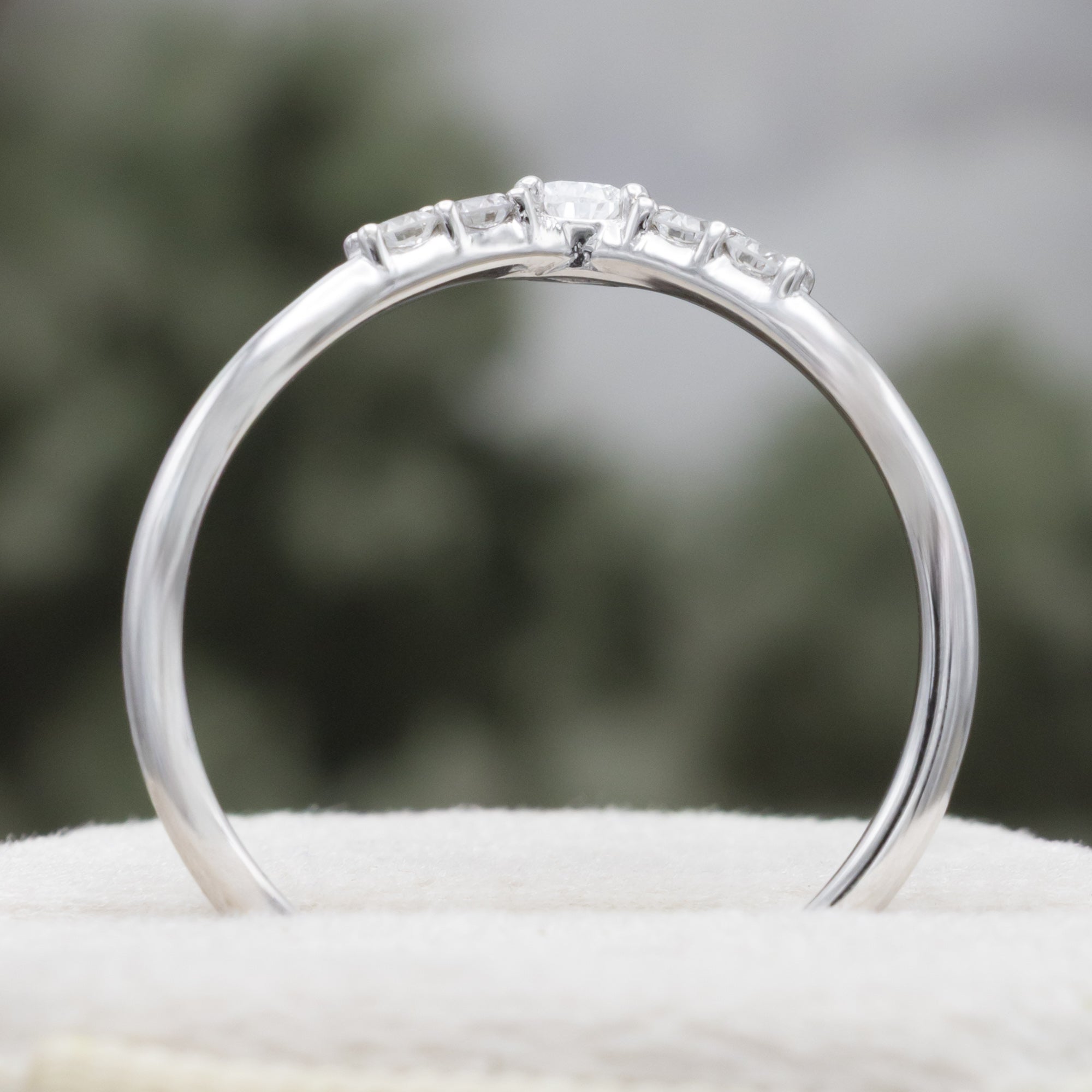 White gold ring with diamond accents on a blurred natural background