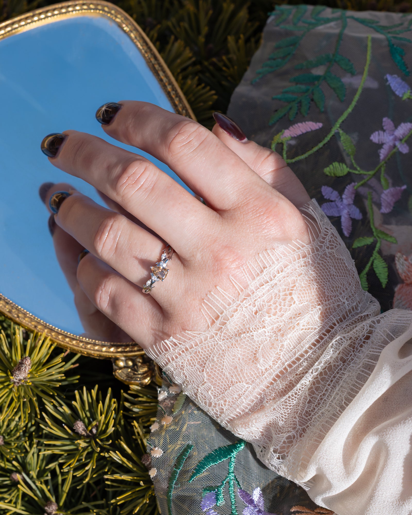 Hand wearing a champagne diamond ring with a decorative background