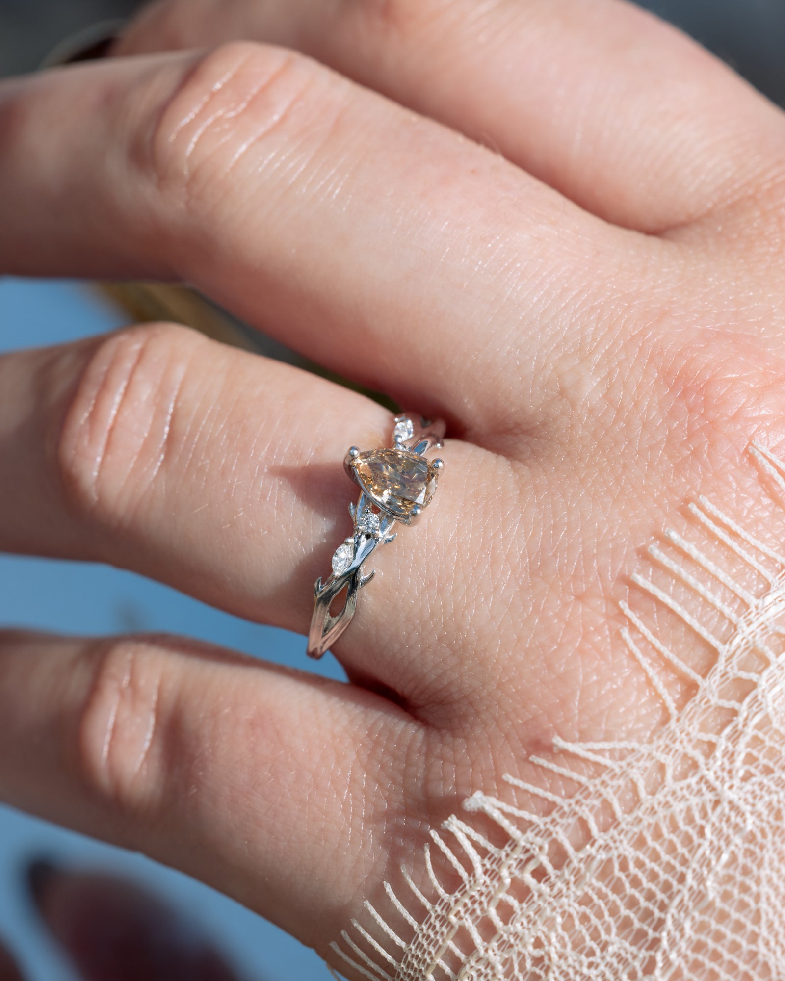 Close-up of a hand wearing a champagne diamond ring with a blurred background