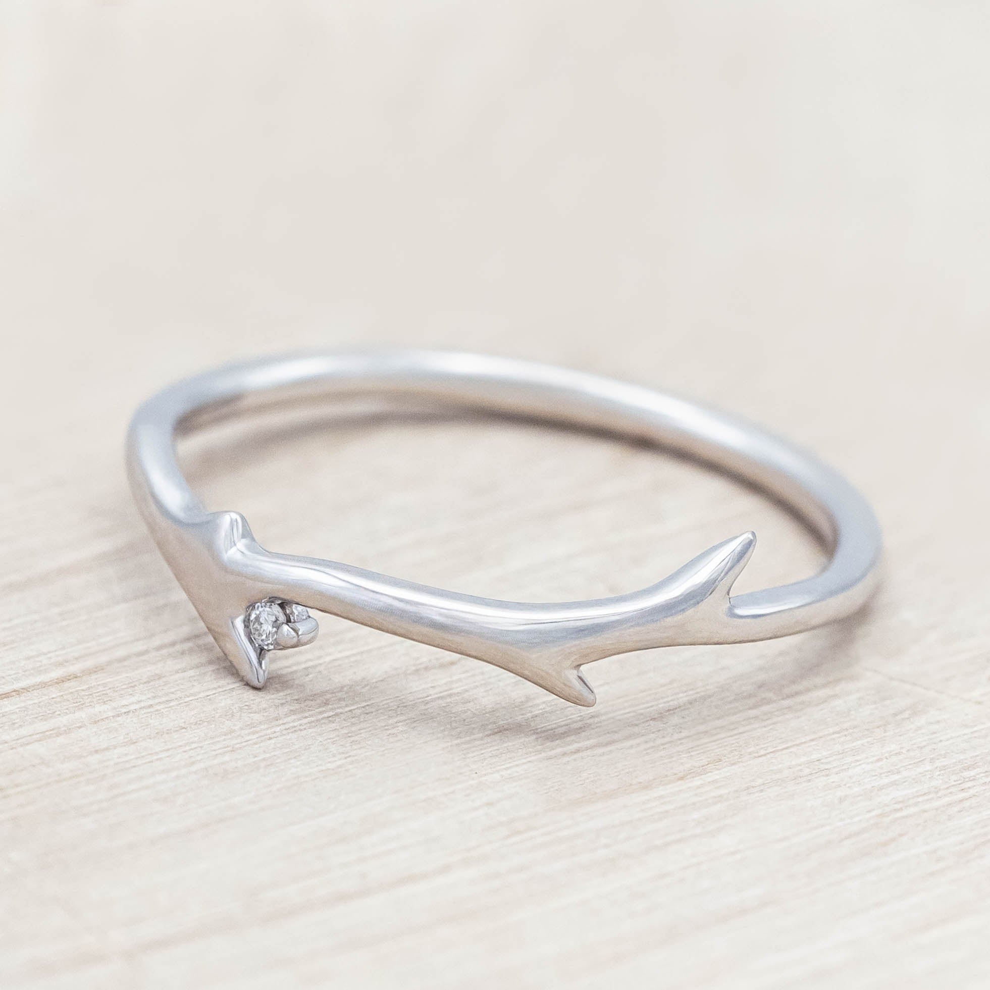 White gold ring with round diamond on a light wooden background
