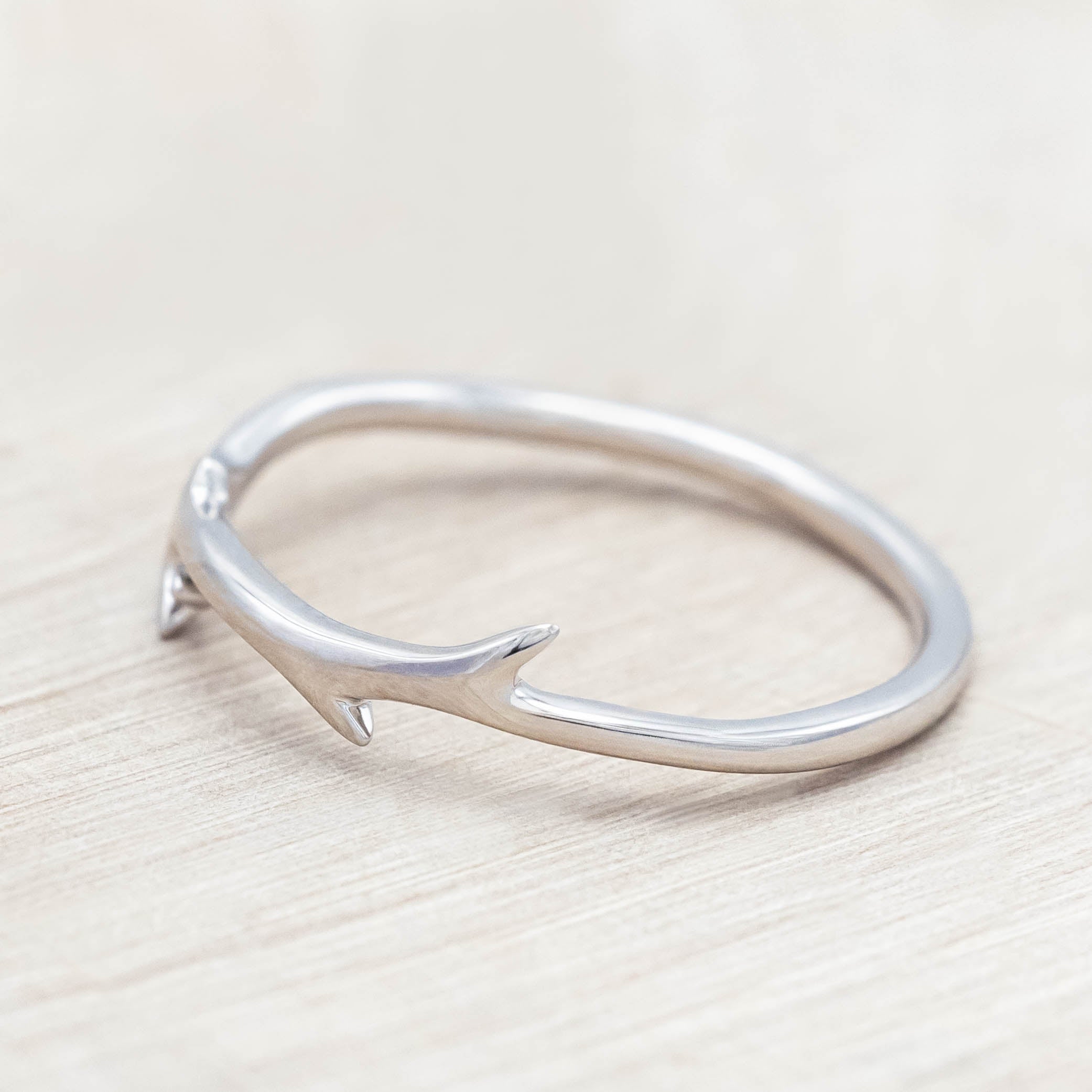 White gold ring with round diamond on a light wood background