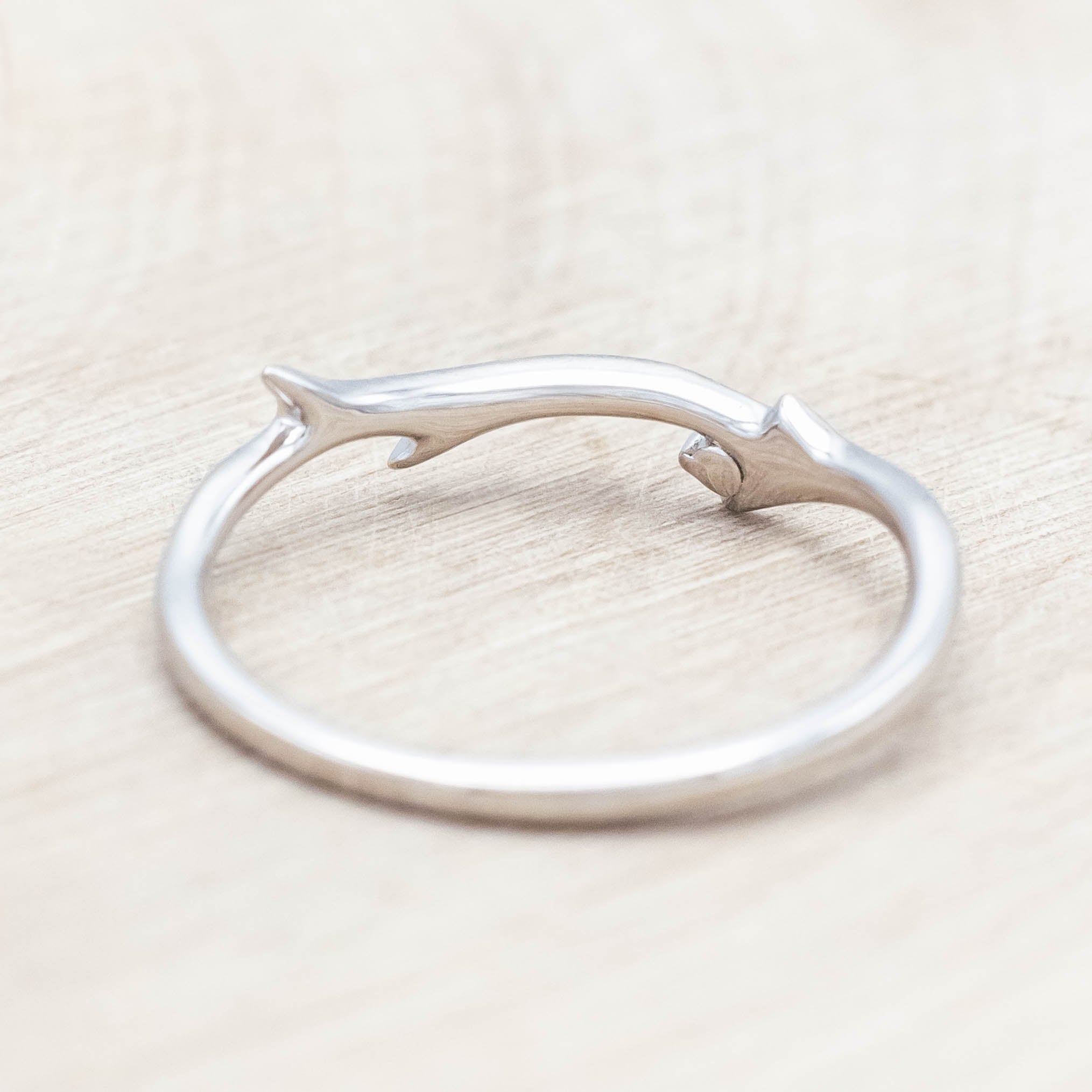 Backside of white gold ring with round diamond on a light wood background