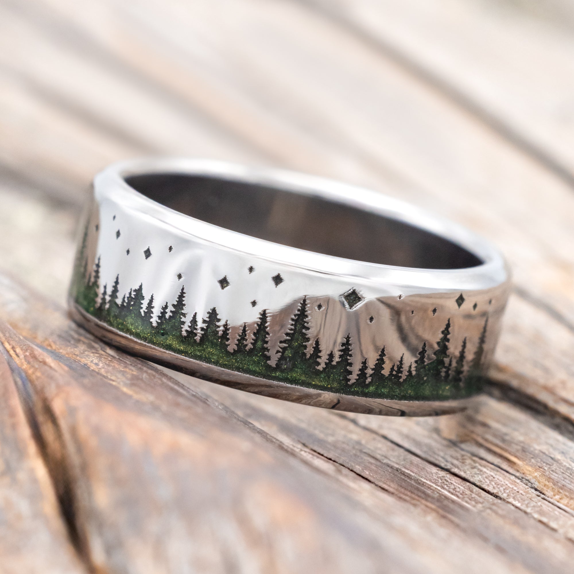 Ring with mountain and forest design with green mica powder on a wooden surface