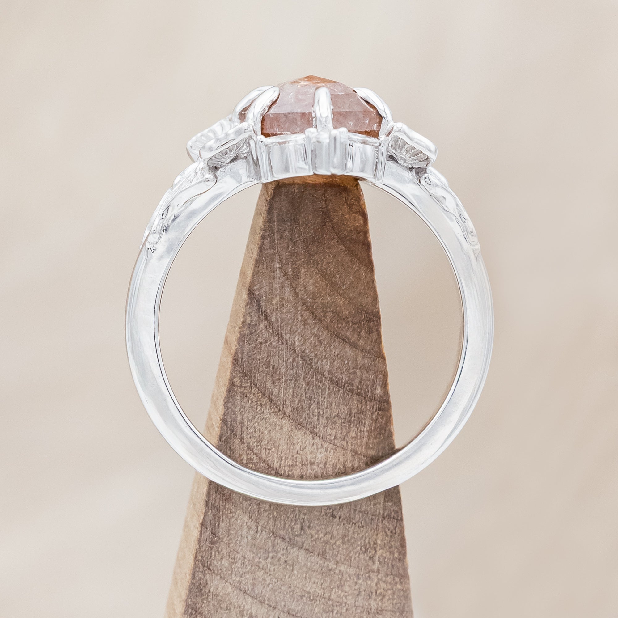 White gold ring with a salt & pepper diamond and moth design on a beige background