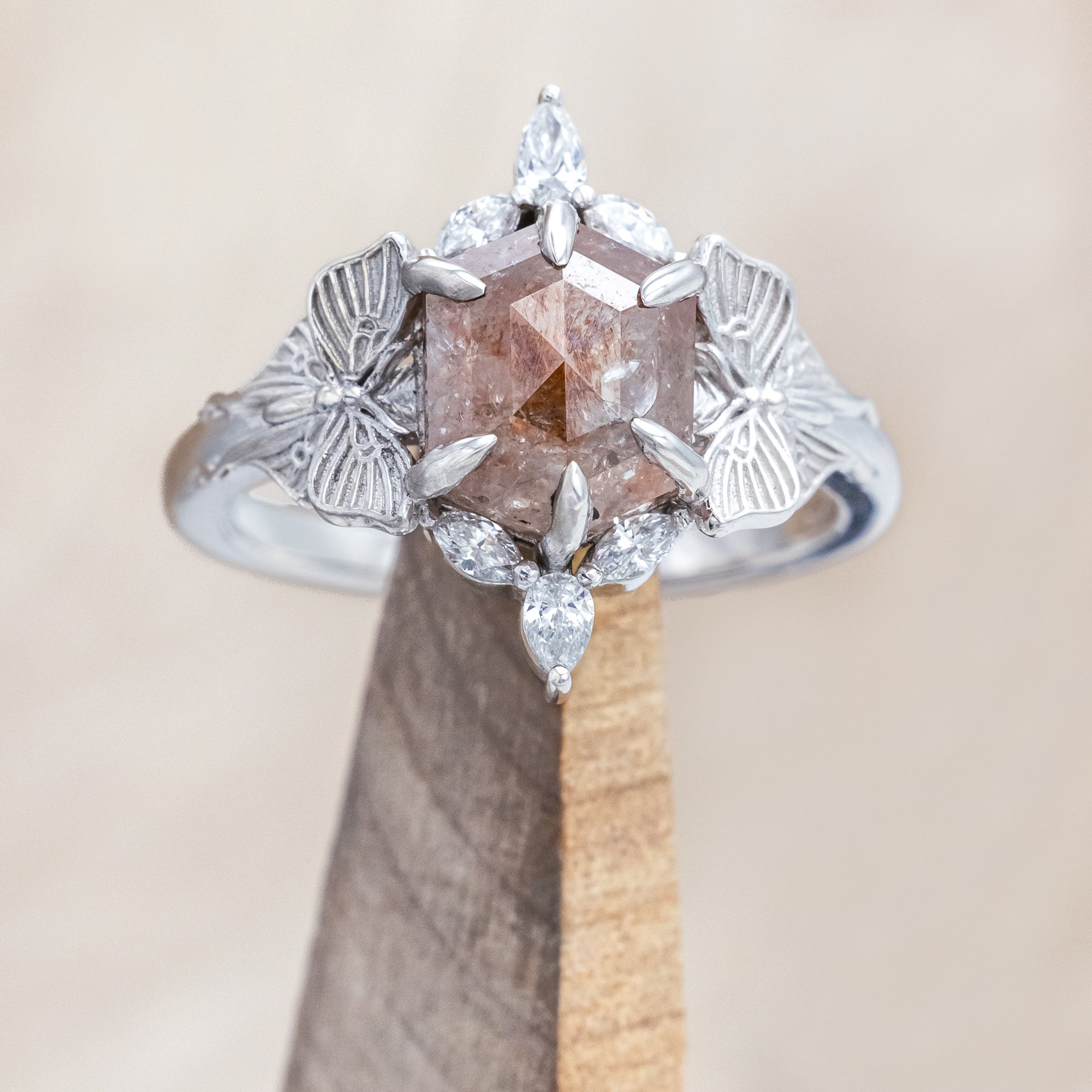 White gold ring with a salt & pepper diamond and moth design on a beige background