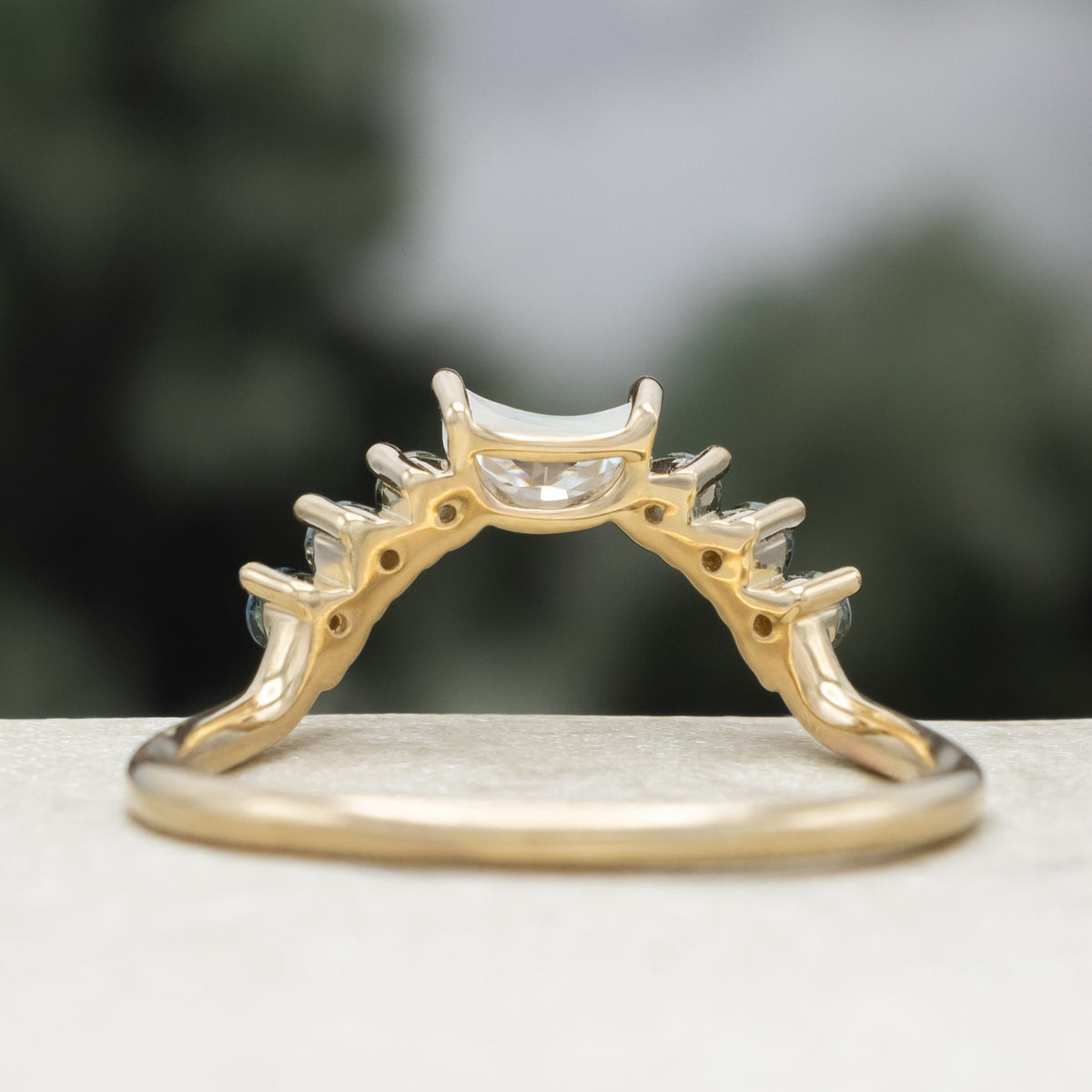 Gold ring tracer with moissanite and Montana sapphire accents against a blurred background