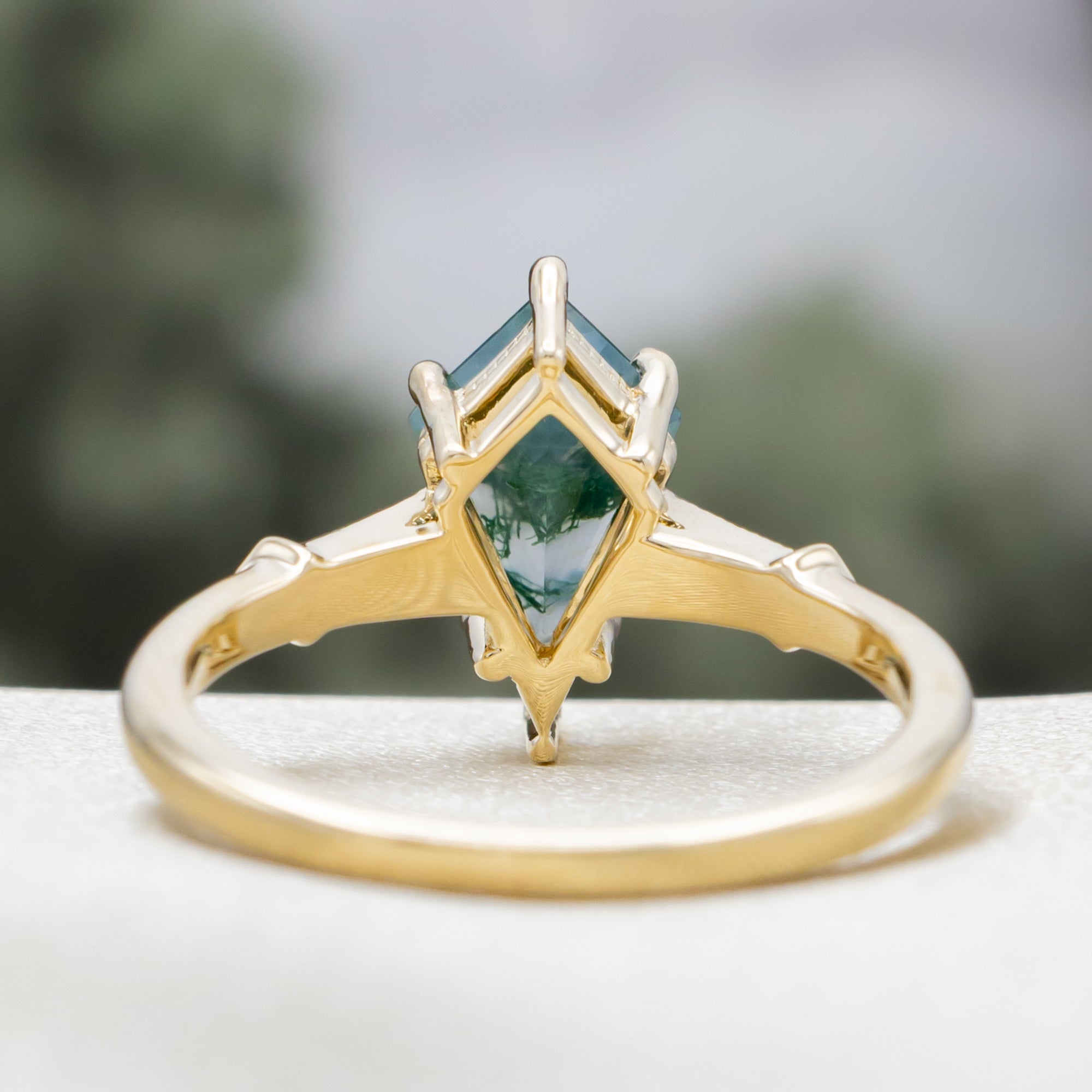 Gold ring with a moss agate centerstone & diamond accents on a blurred background