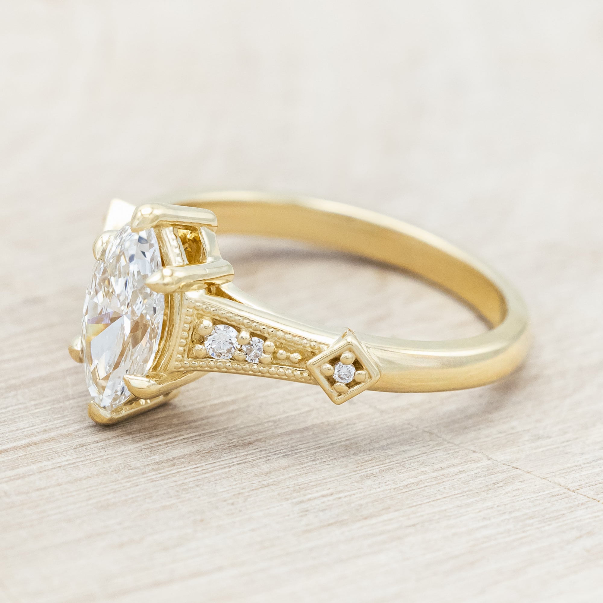 14K gold ring with lab-grown diamond center stone & accents on a light wooden background