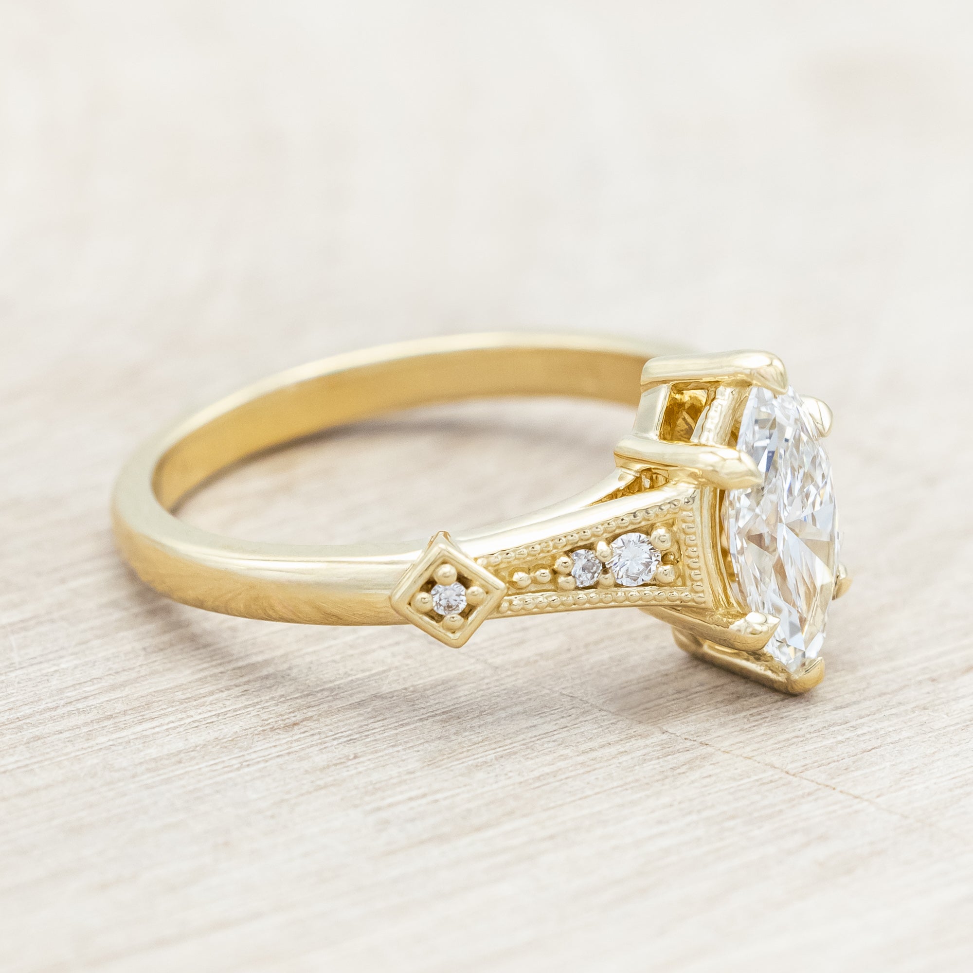 14K gold ring with lab-grown diamond center stone & accents on a light wooden background