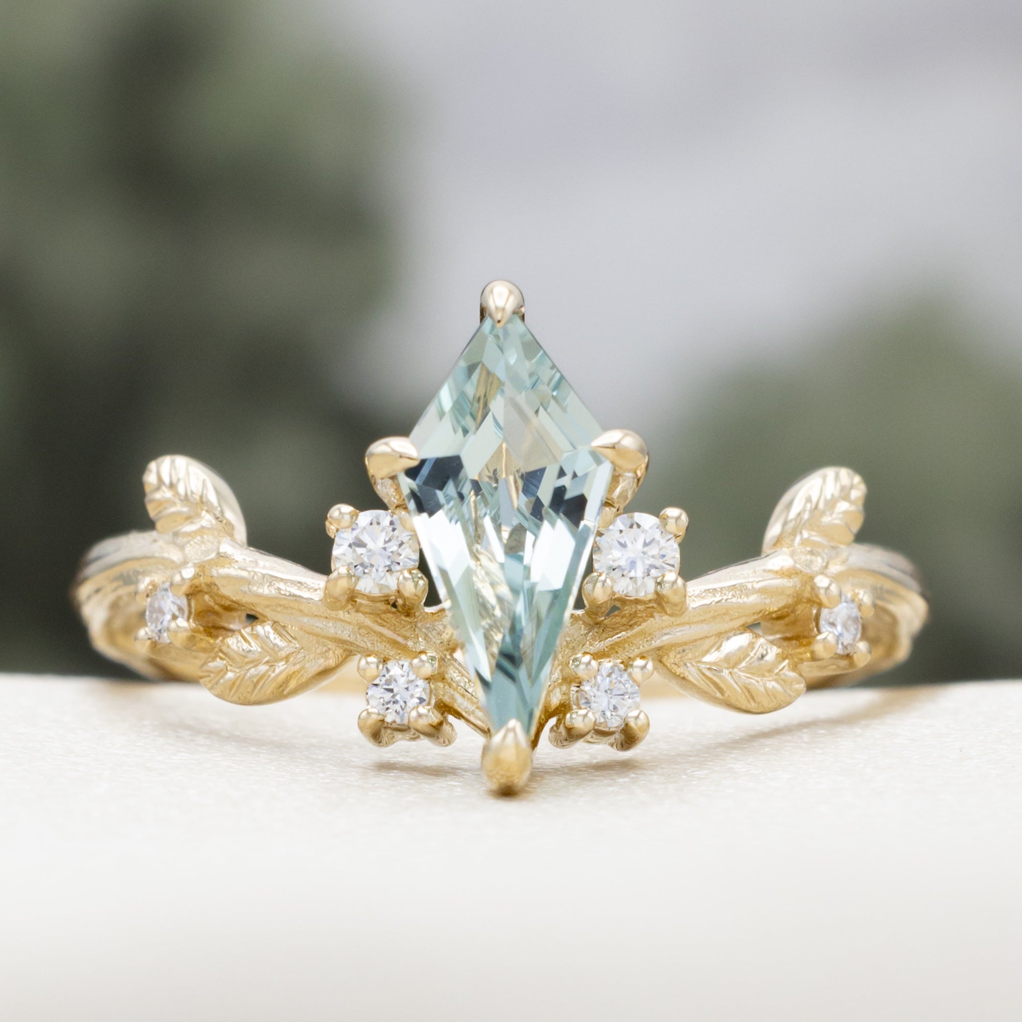 Gold ring with moss agate and diamond accents on a white surface.