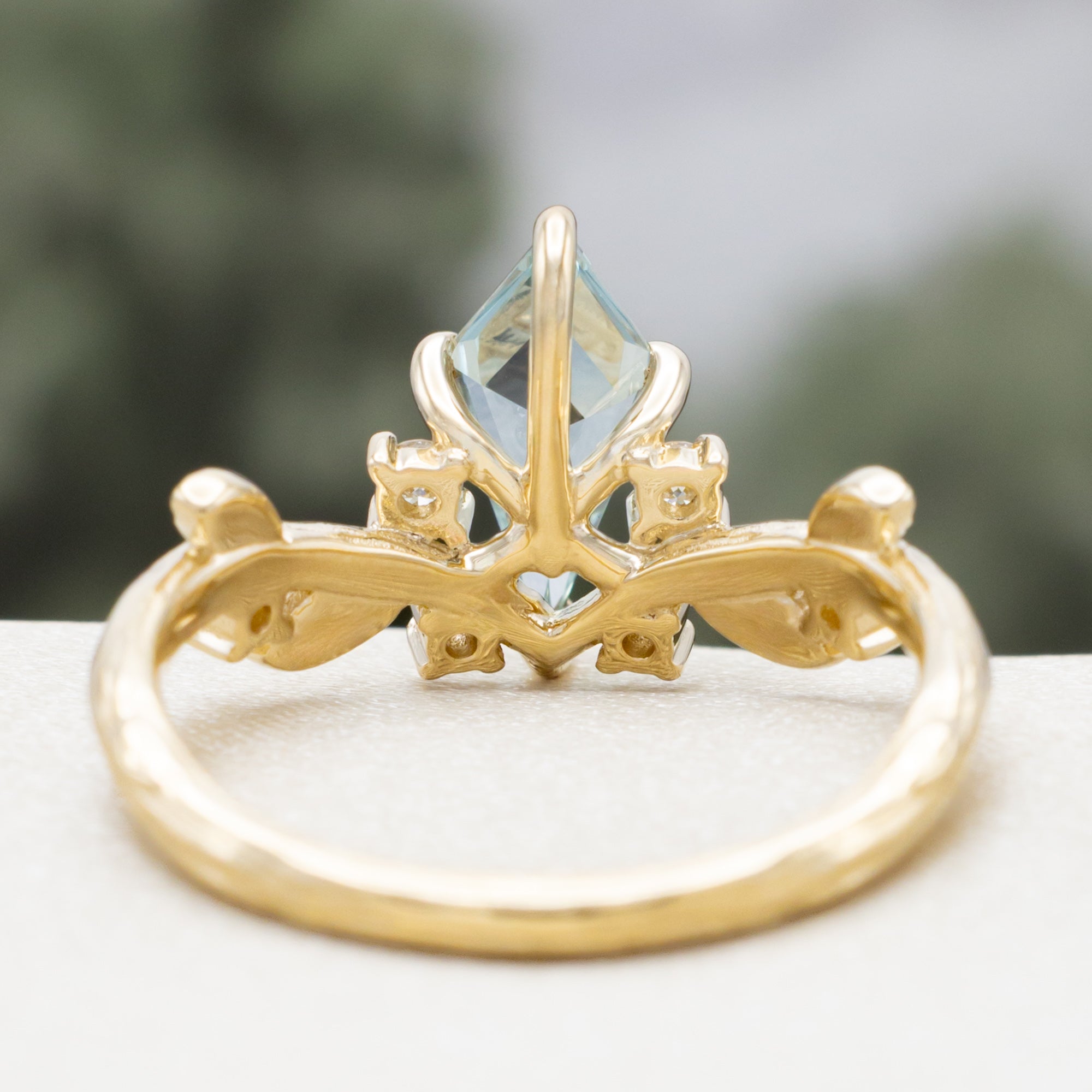 Gold ring with moss agate and diamond accents on a white surface.