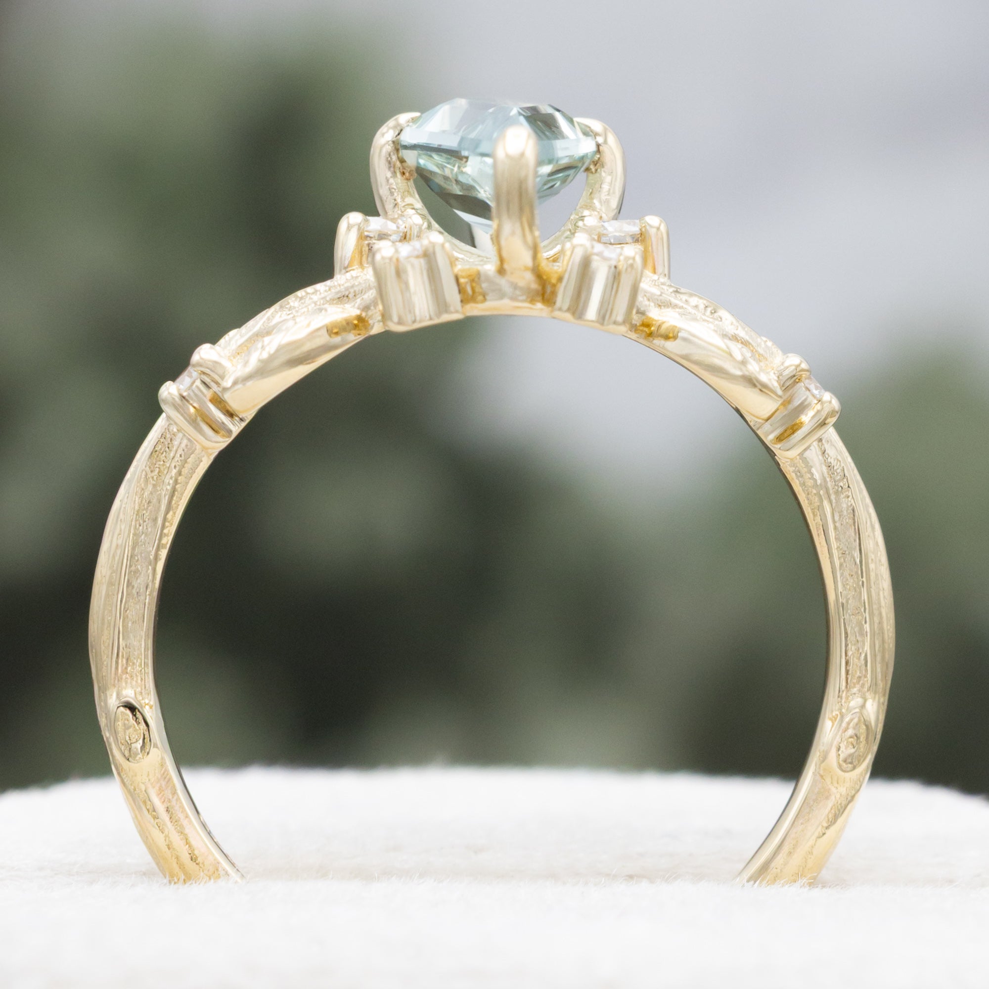 Gold ring with moss agate and diamond accents on a white surface.