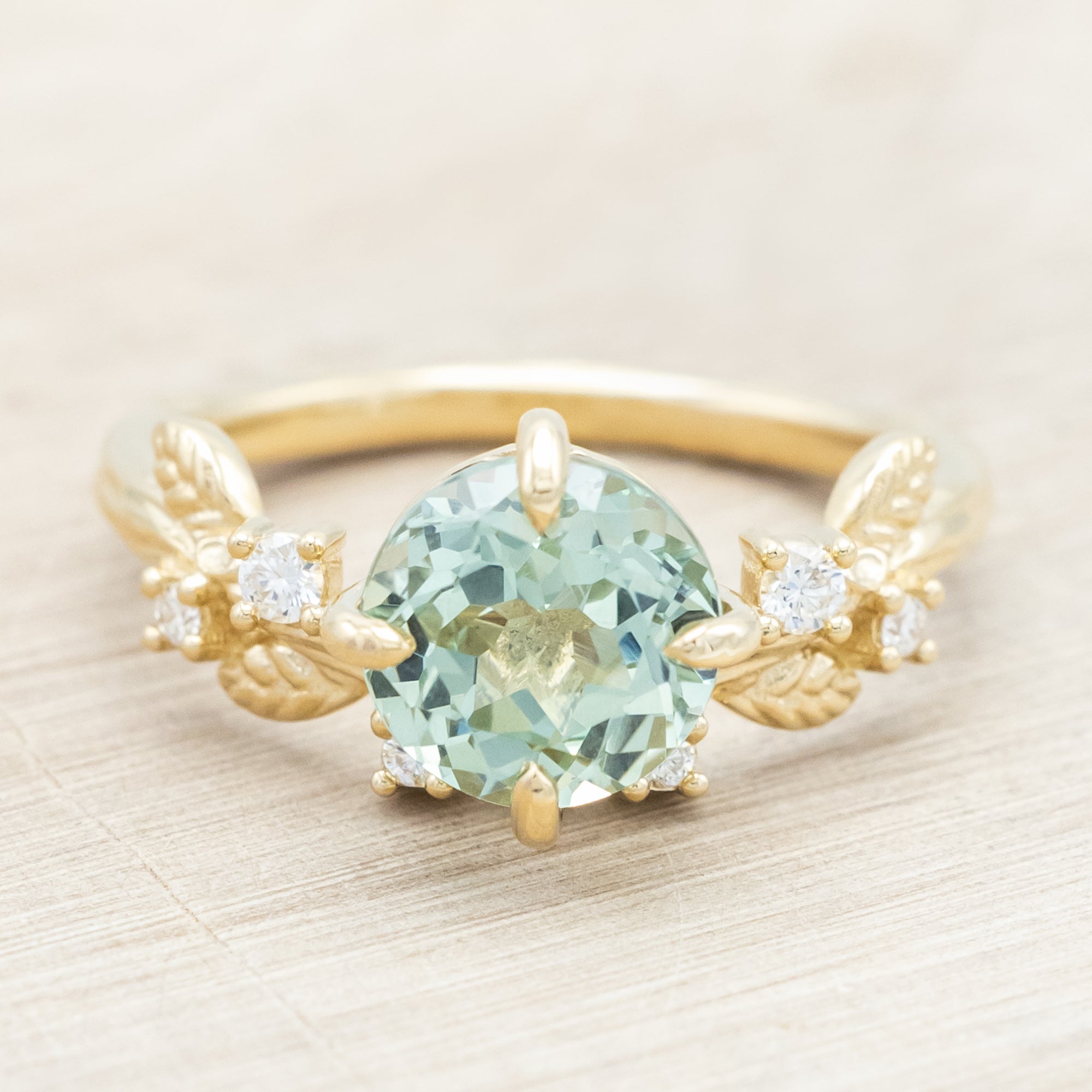 Yellow gold ring with a large sapphire and diamond accents on a neutral background