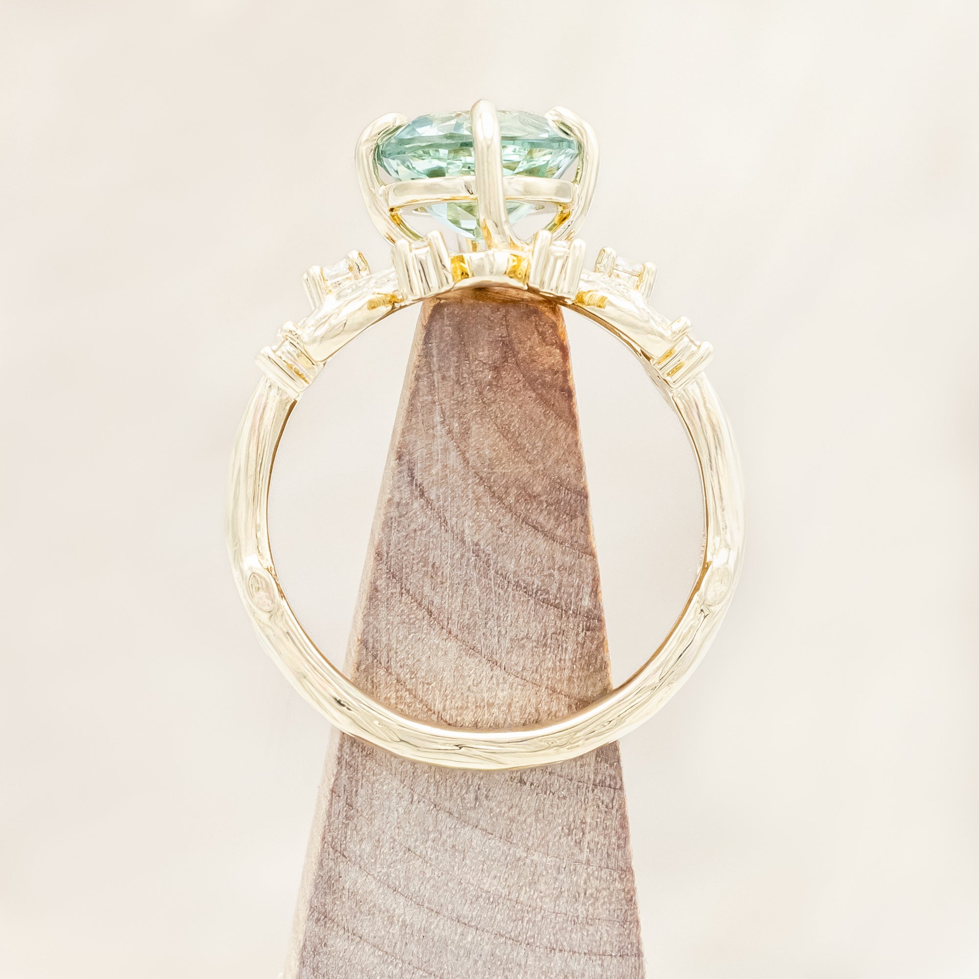 Yellow gold ring with a large sapphire and diamond accents on a neutral background