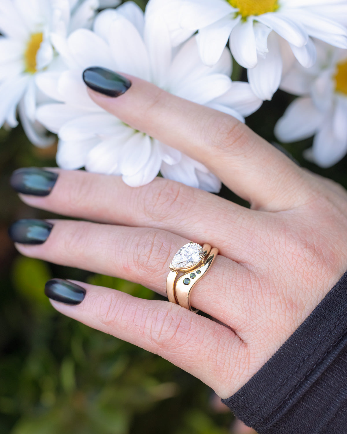 On hand photo of "Sybil" - asymmetrical solitaire-style lab diamond women's engagement ring with green tourmaline tracer