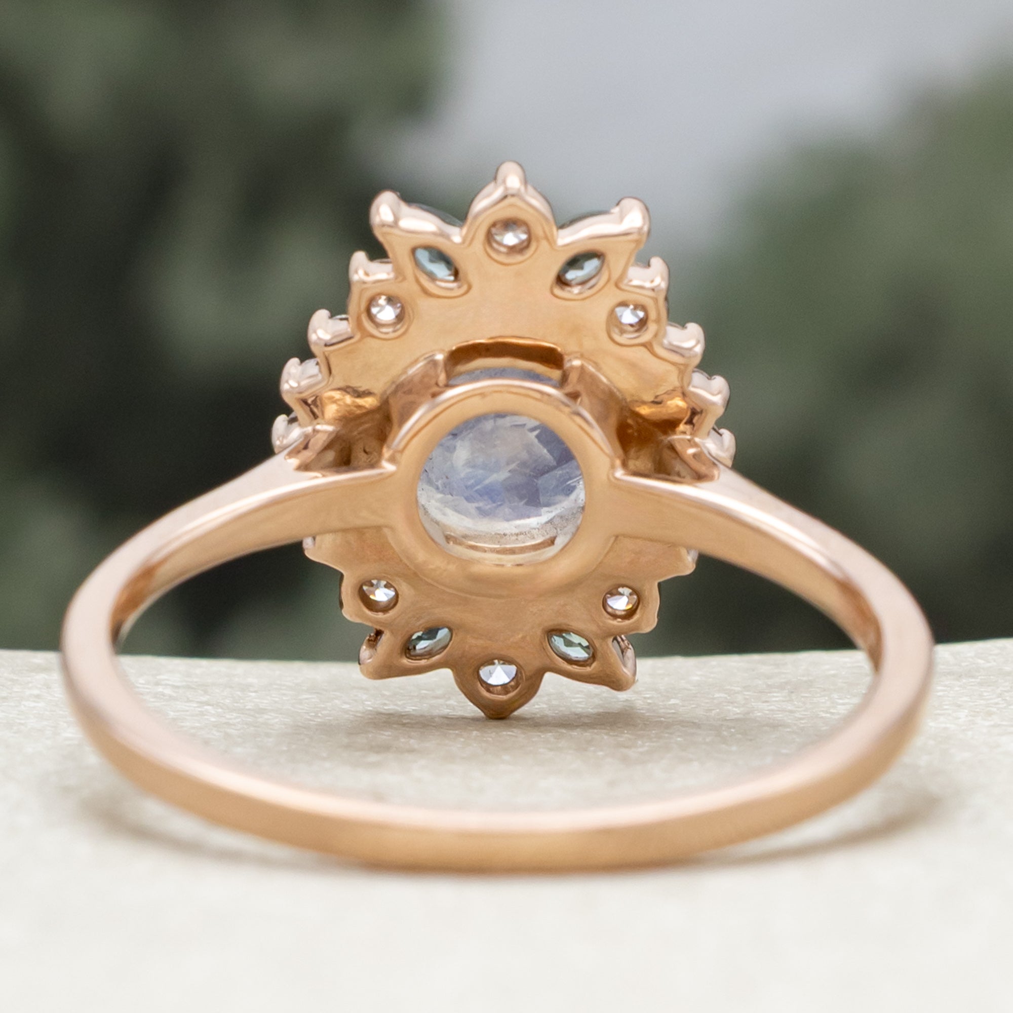 Rose gold ring with a central moonstone and gemstone accents on a neutral background