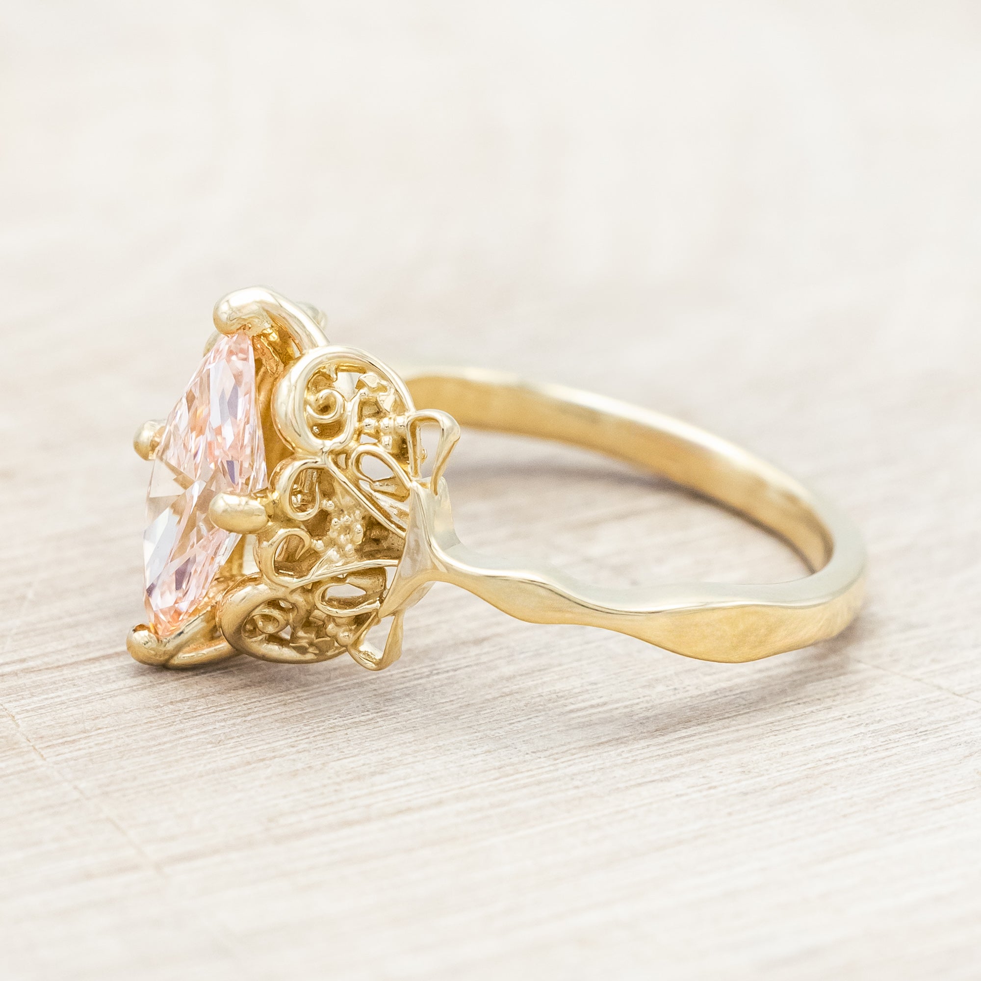14K yellow gold ring with a pink lab diamond on a neutral background