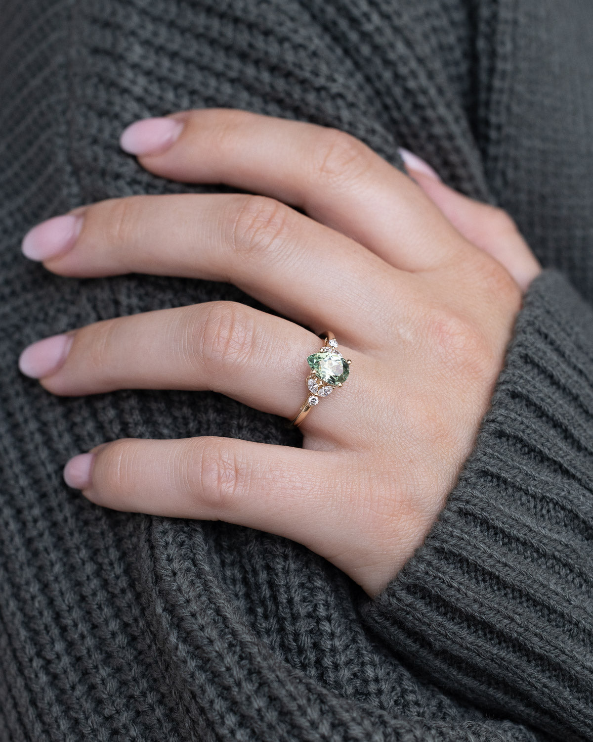 On hand image of "Blossom" - pear cut lab-grown green sapphire women's engagement ring with diamond accents