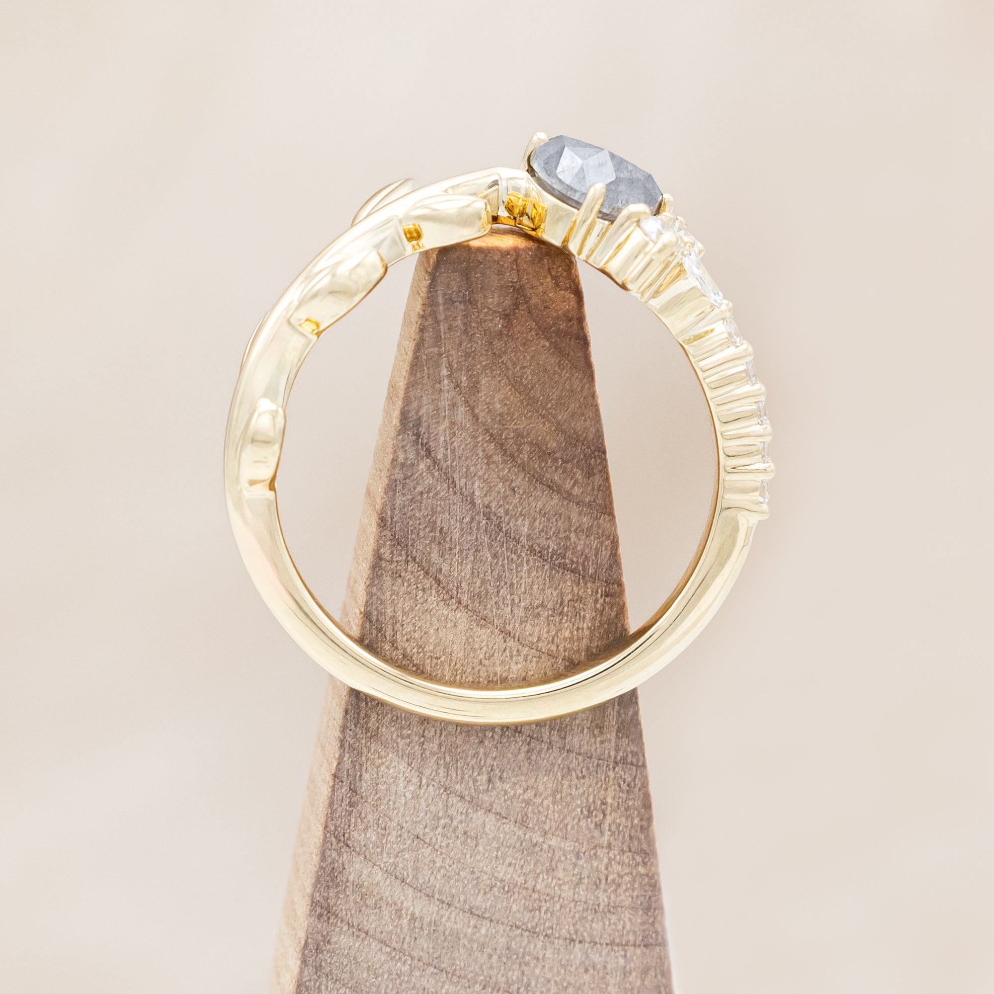 14K gold tracer with leaf design and diamond accents on a wooden stand against a wooden stand
