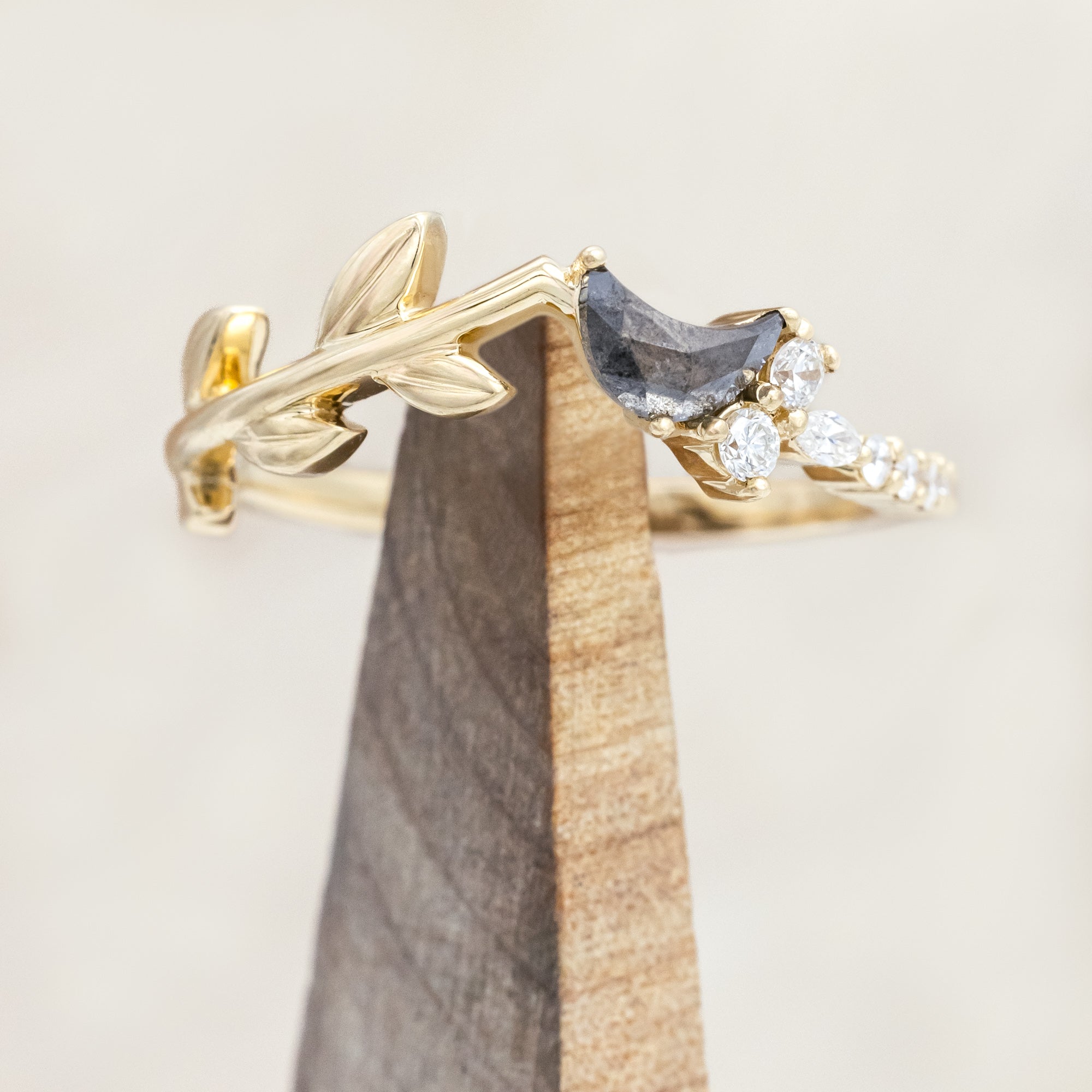 14K gold tracer with leaf design and diamond accents on a wooden stand against a light background