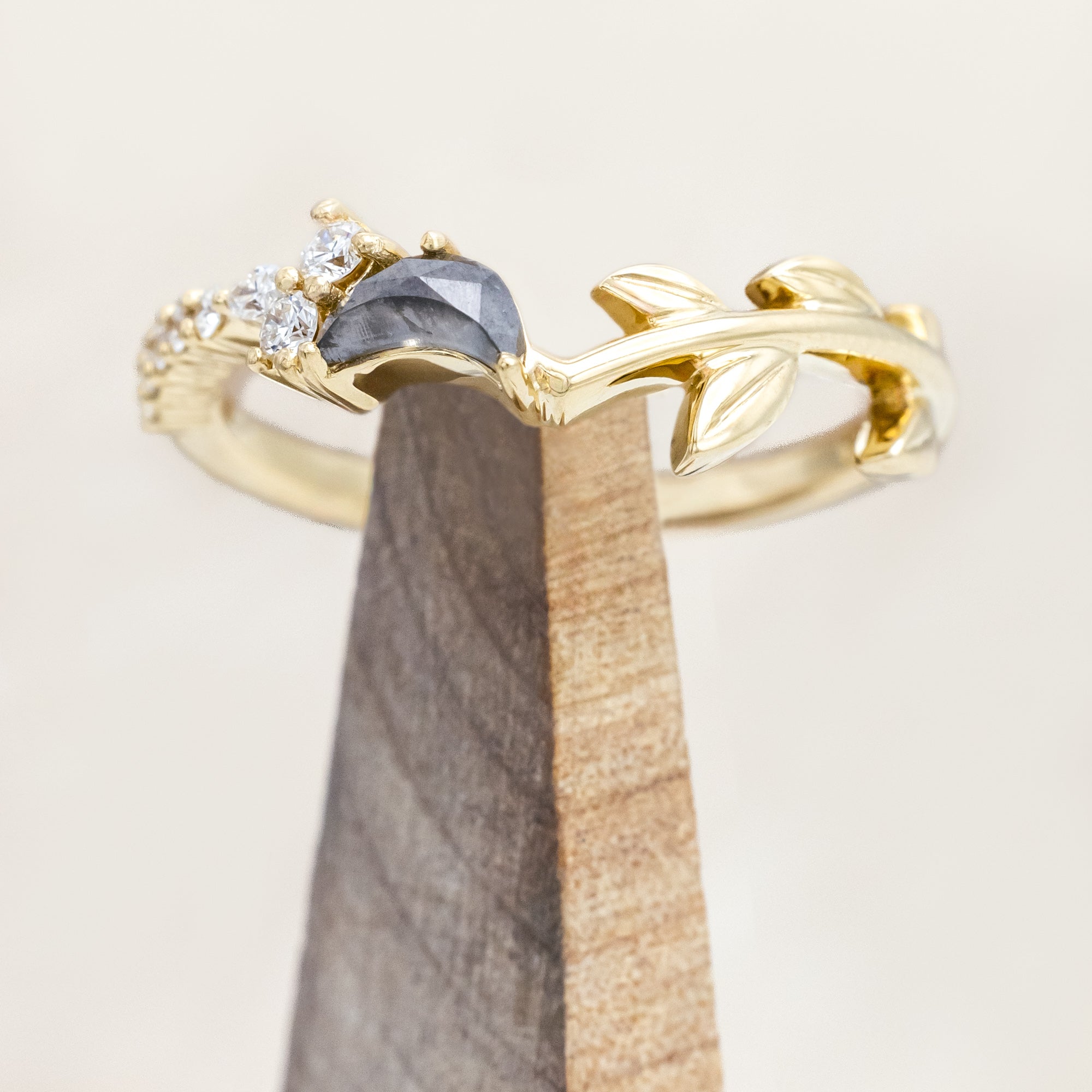 14K gold tracer with leaf design and diamond accents on a wooden stand against a light background