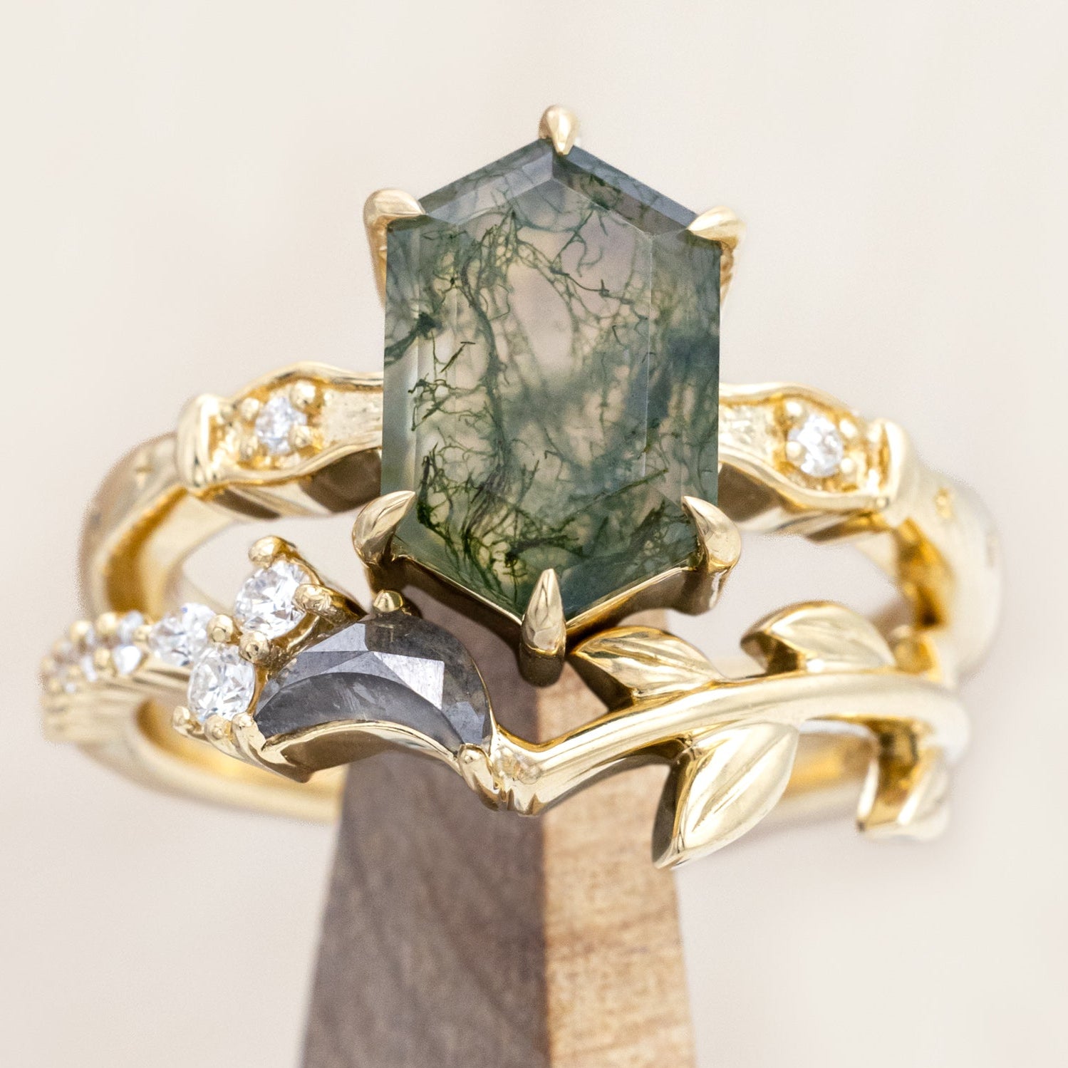 14K gold ring with a moss agate and salt & pepper diamond tracer on a wooden stand