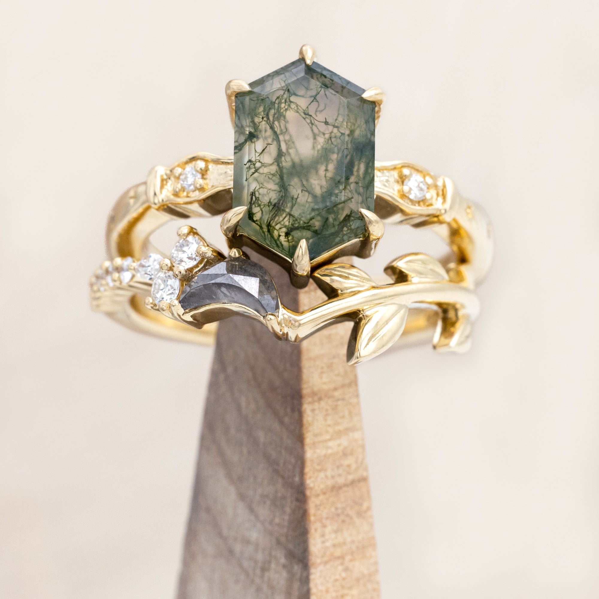 14K gold ring with a moss agate and salt & pepper diamond tracer on a wooden stand