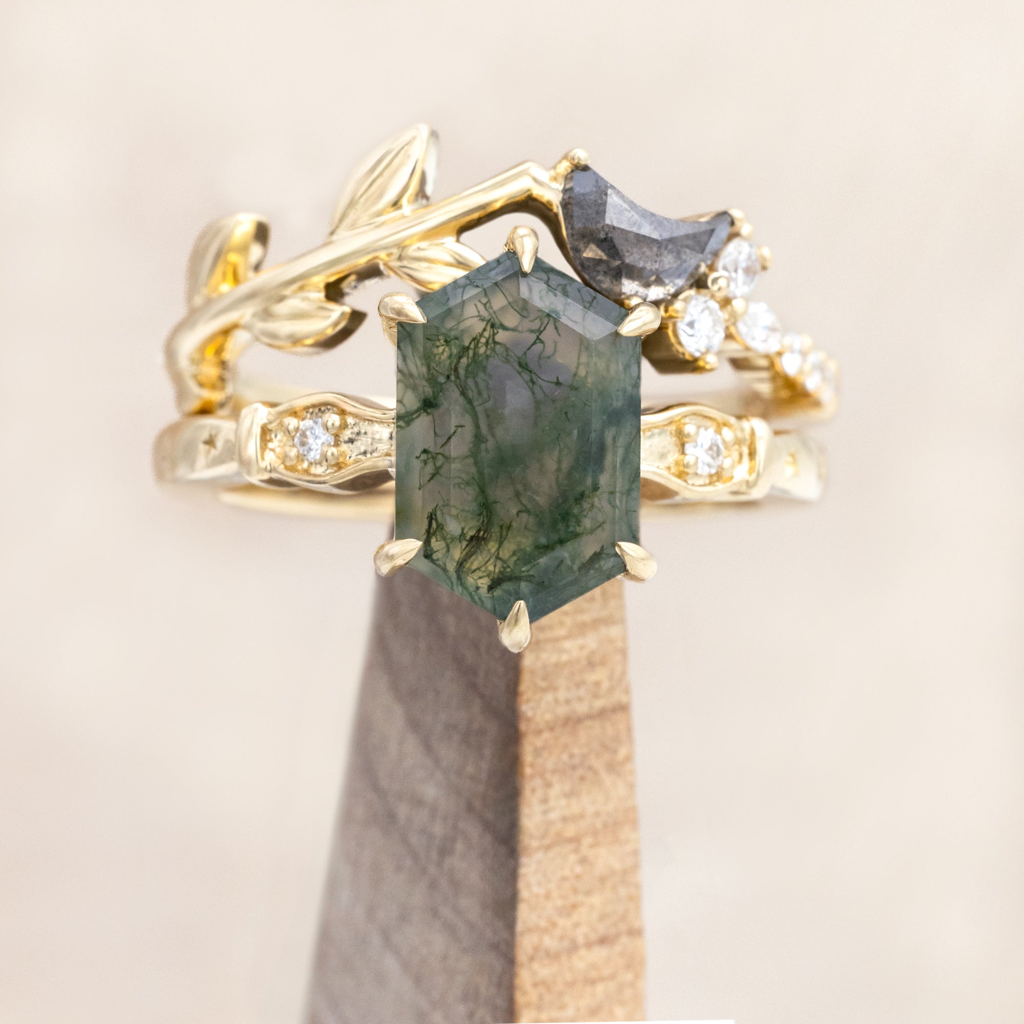 14K gold ring with a moss agate and salt & pepper diamond tracer on a wooden stand
