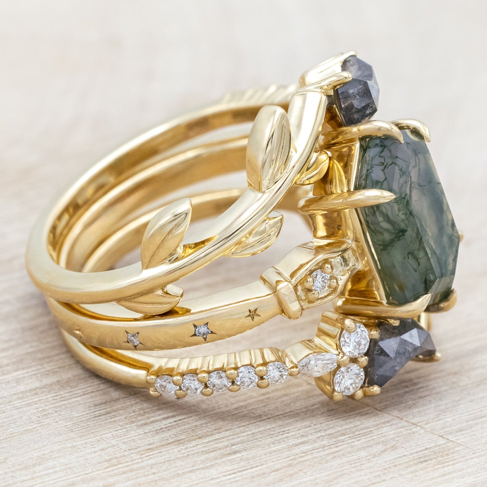 14K gold ring with a moss agate and two salt & pepper diamond tracers on a neutral background