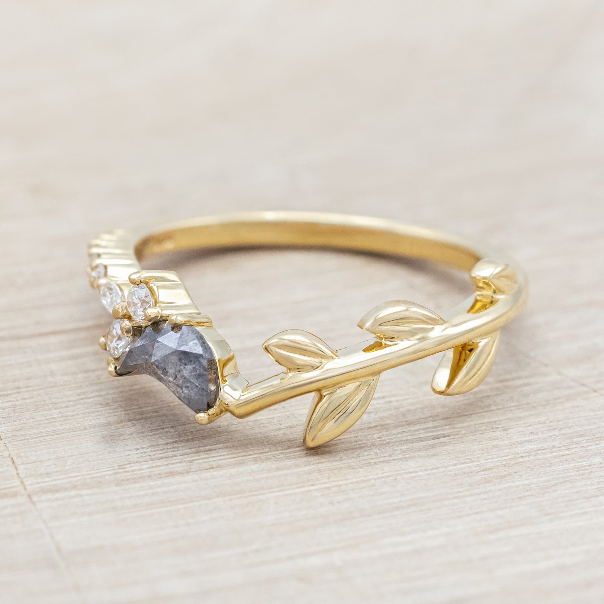 14K gold tracer with leaf design and diamond accents on a wooden stand against a light background