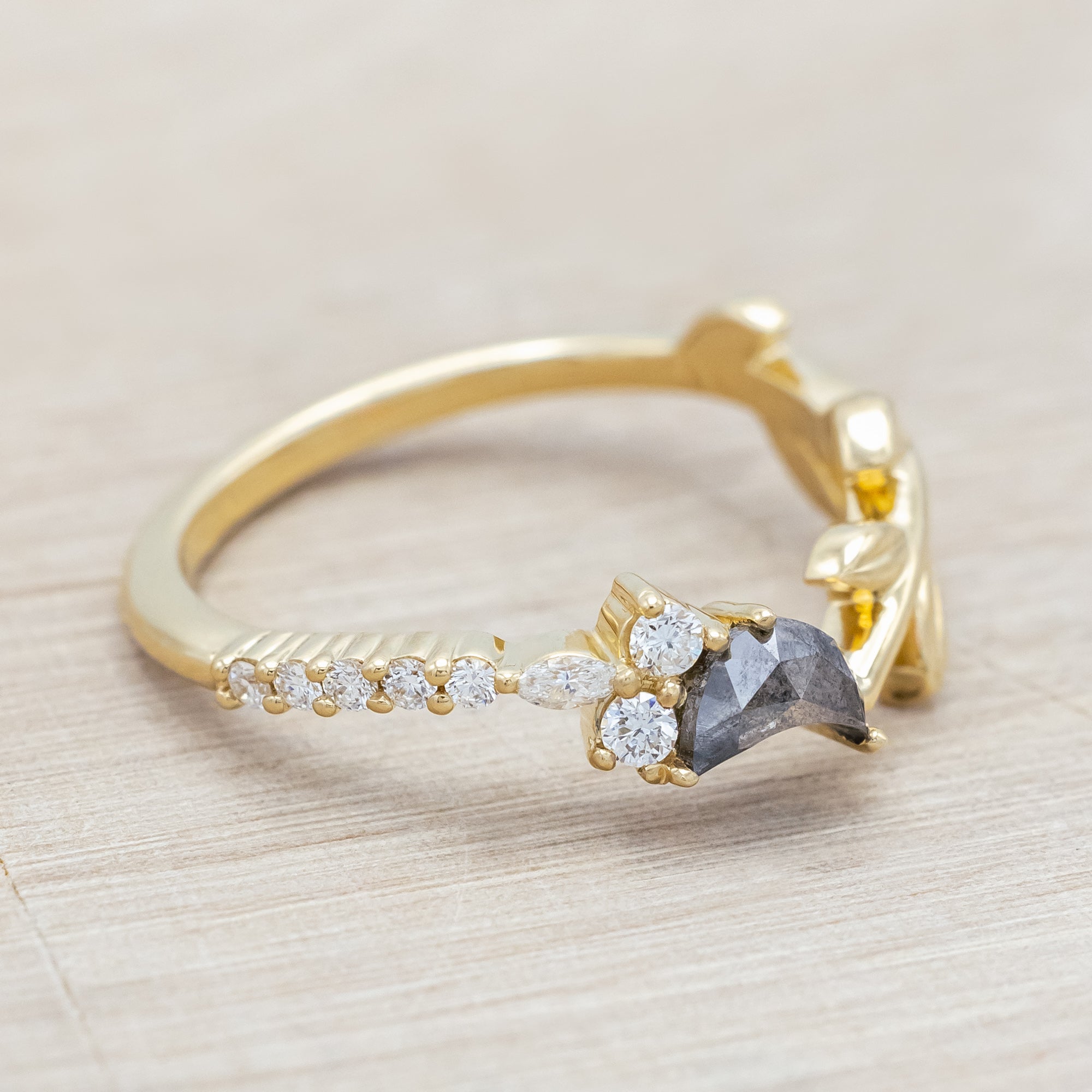 14K gold tracer with leaf design and diamond accents on a wooden stand against a light background