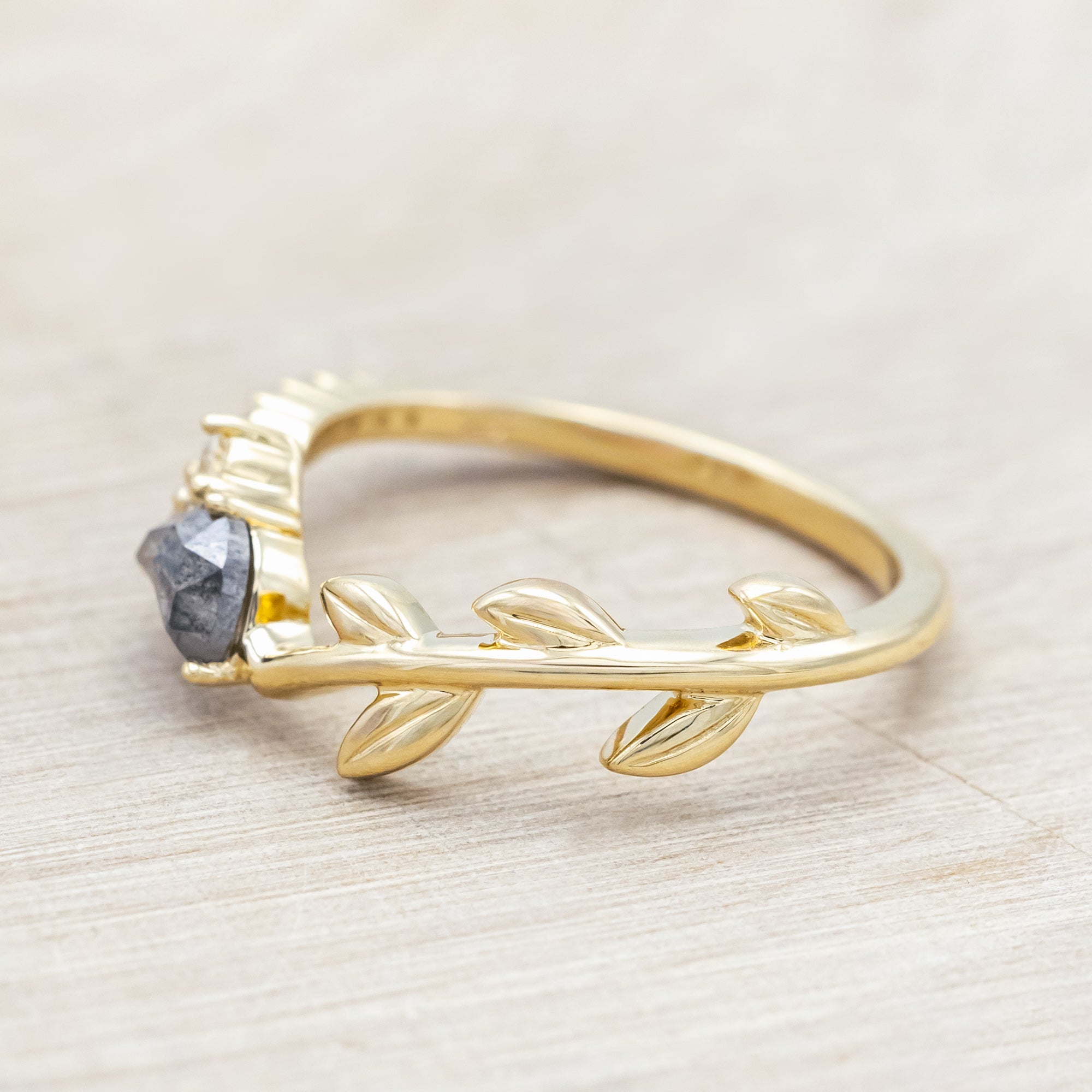 14K gold tracer with leaf design and diamond accents on a wooden stand against a light background