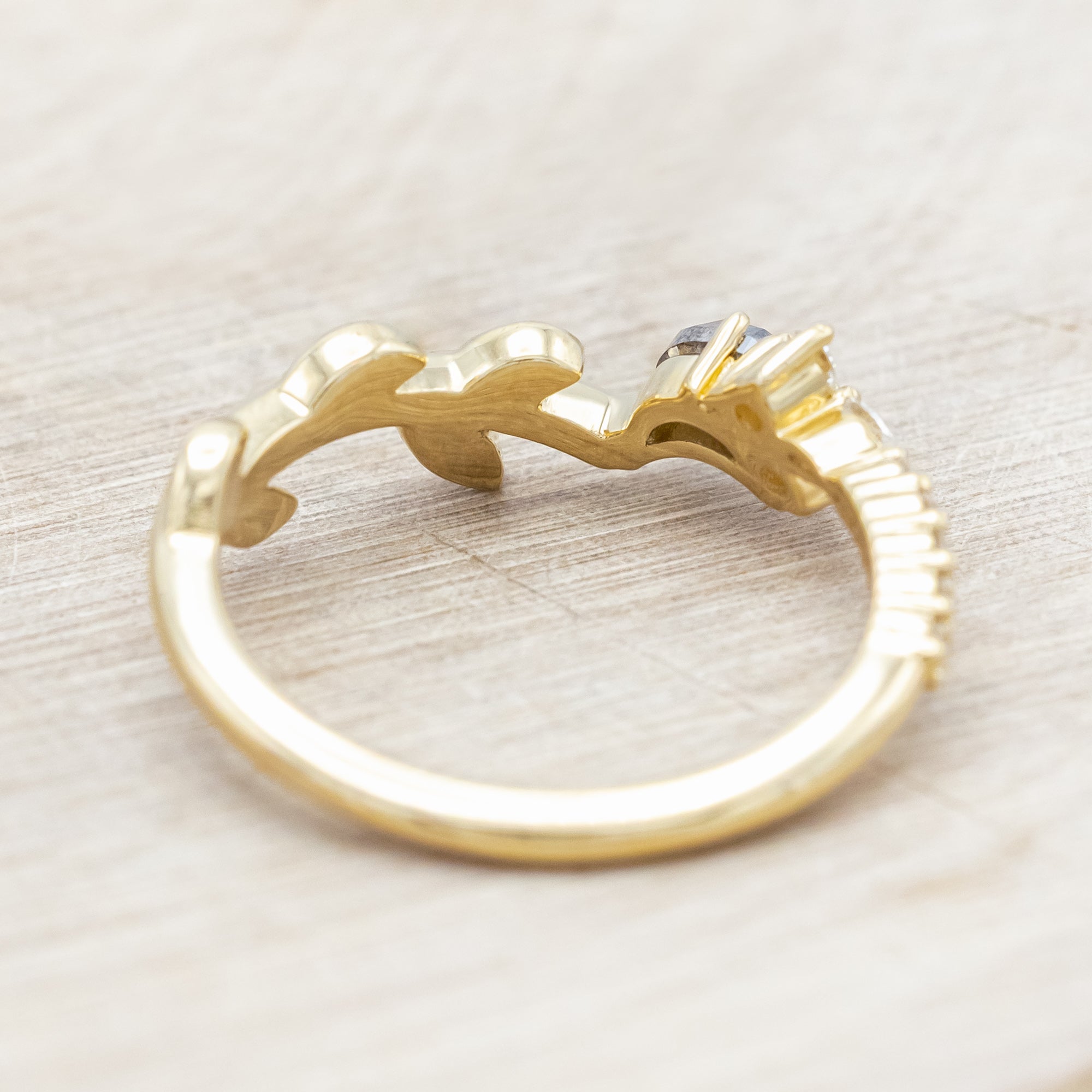 14K gold tracer with leaf design and diamond accents on a wooden stand against a light background
