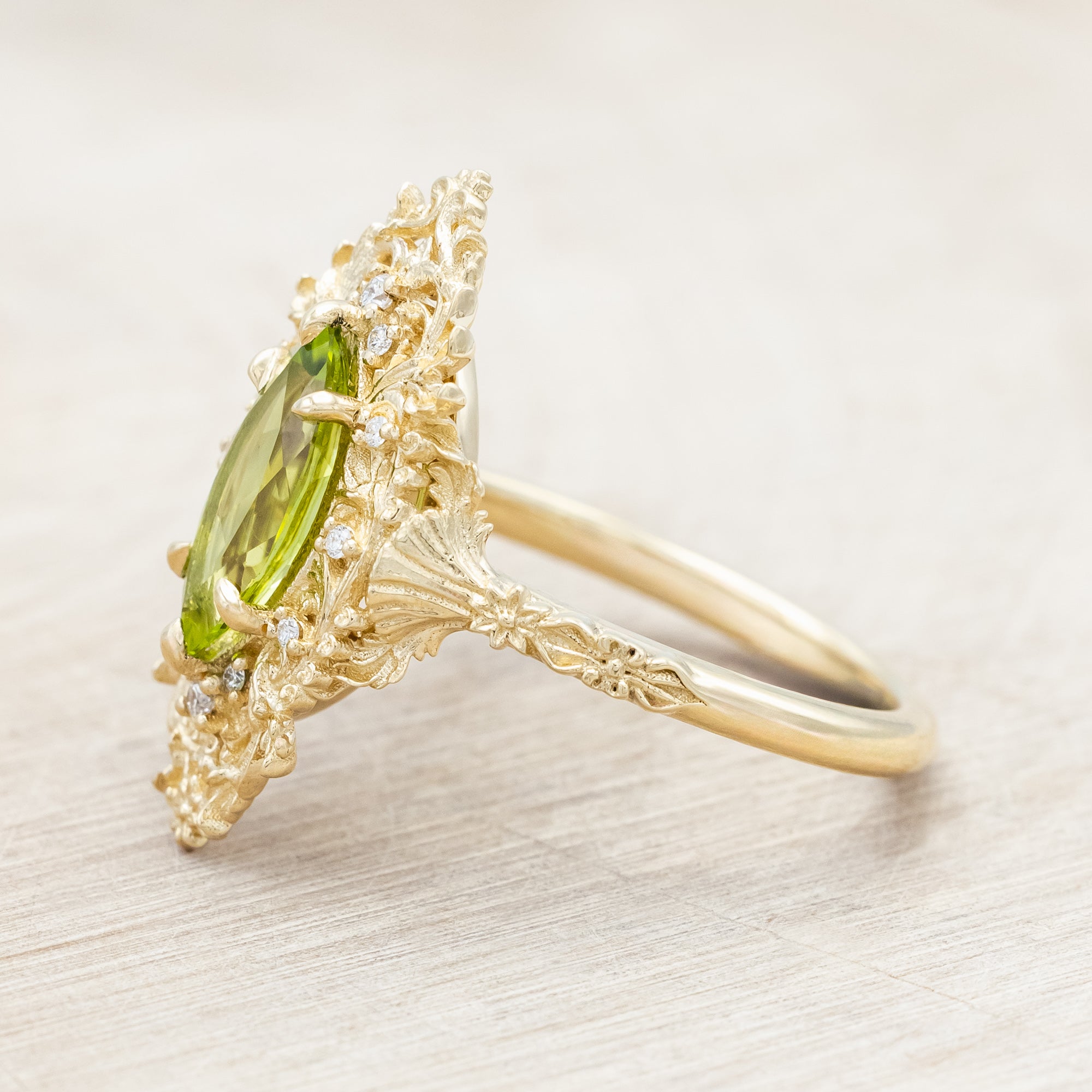 Yellow gold ring with a green peridot on a beige background