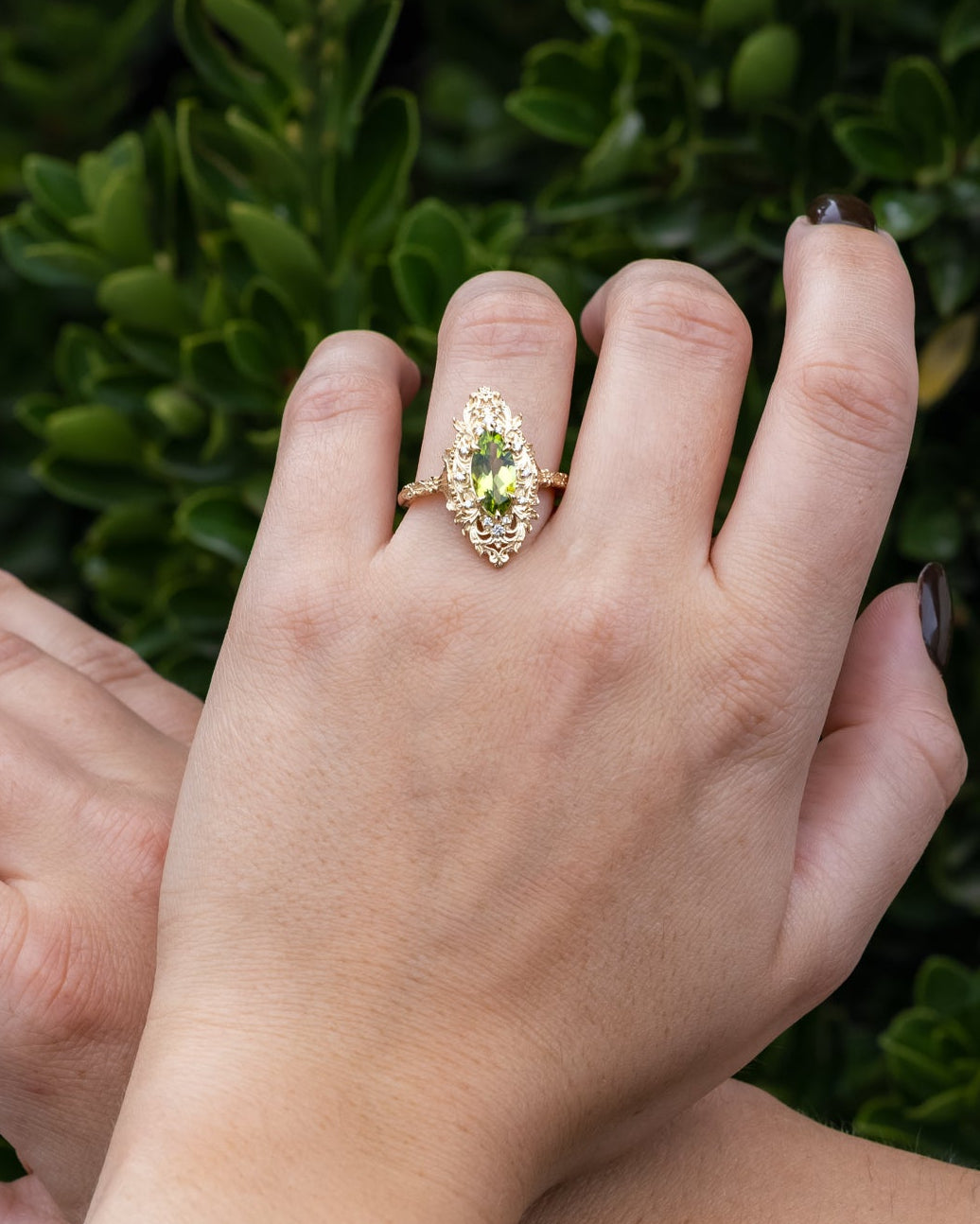 Close-up of hands with a ring on a green leafy background