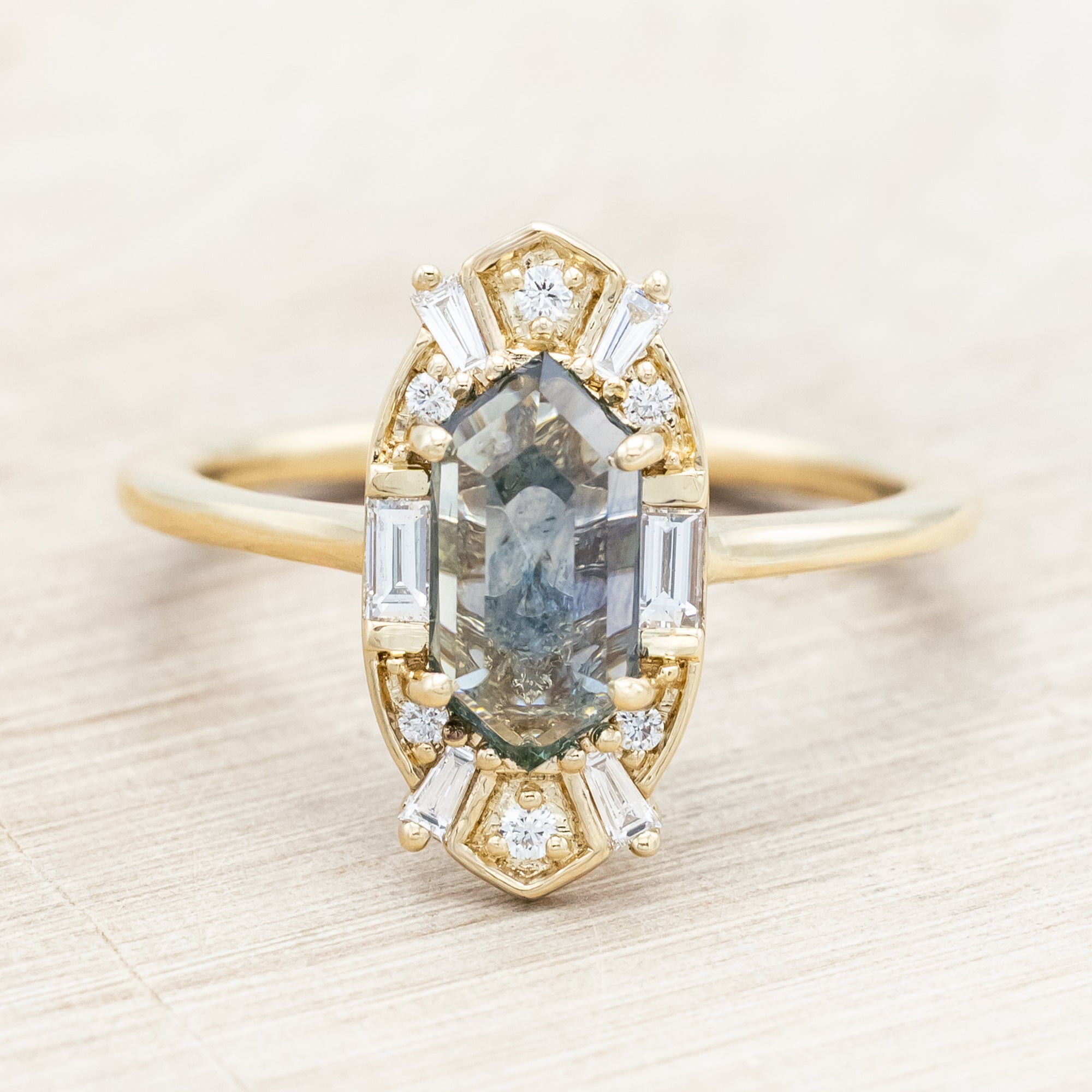 14K gold ring with Montana sapphire and diamond accents on a beige background