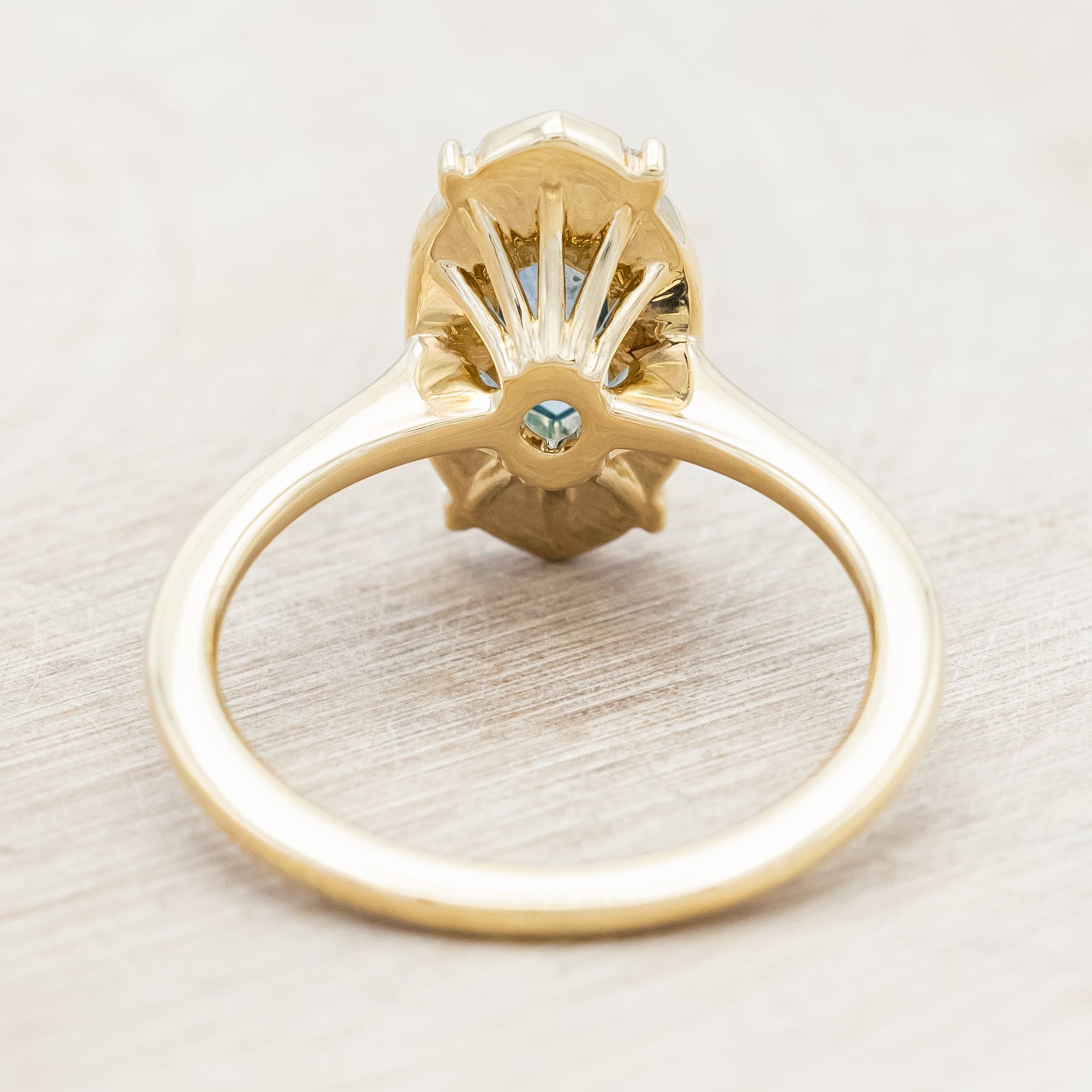 14K gold ring with Montana sapphire and diamond accents on a beige background