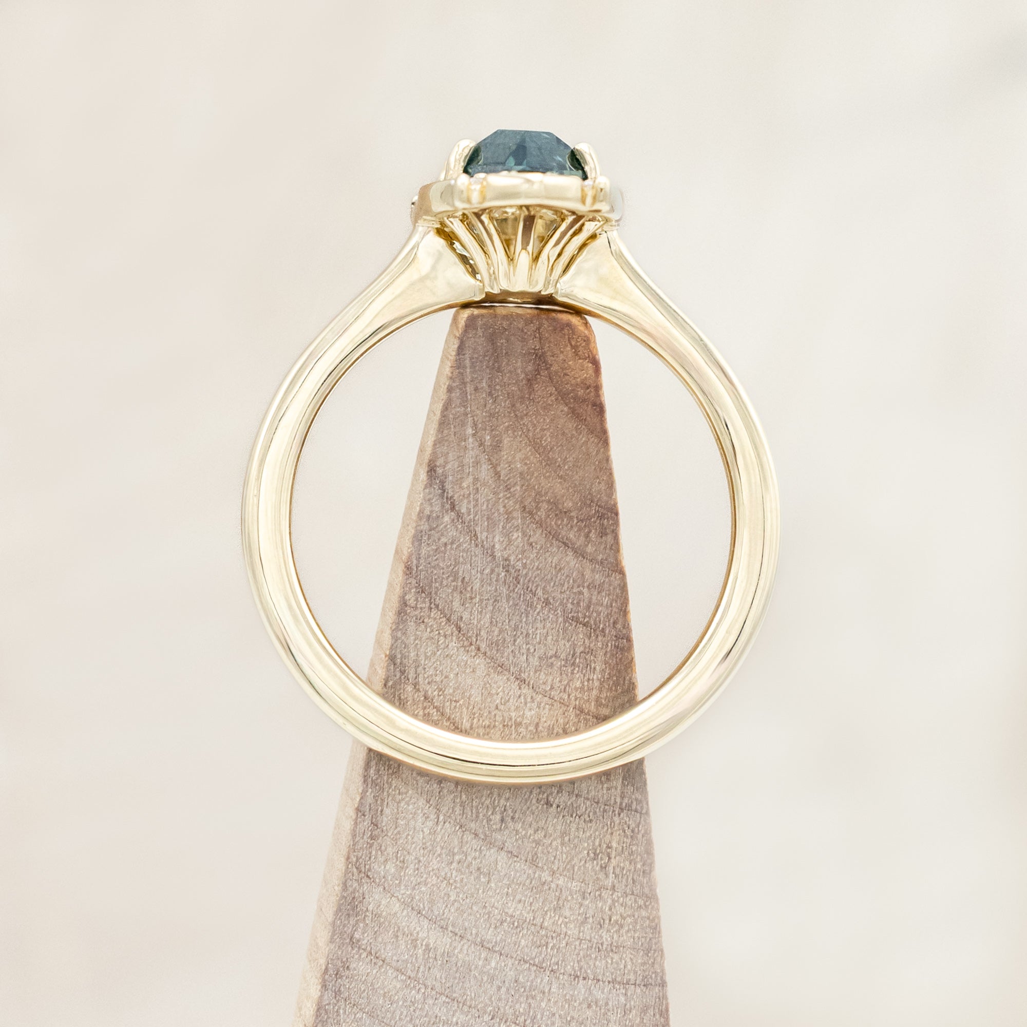 14K gold ring with Montana sapphire and diamond accents on a beige background