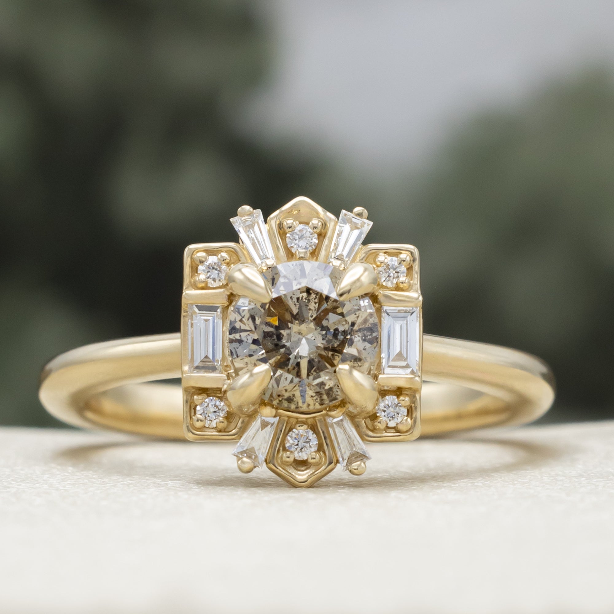 Gold ring with a champagne diamond center stone against a blurred green background