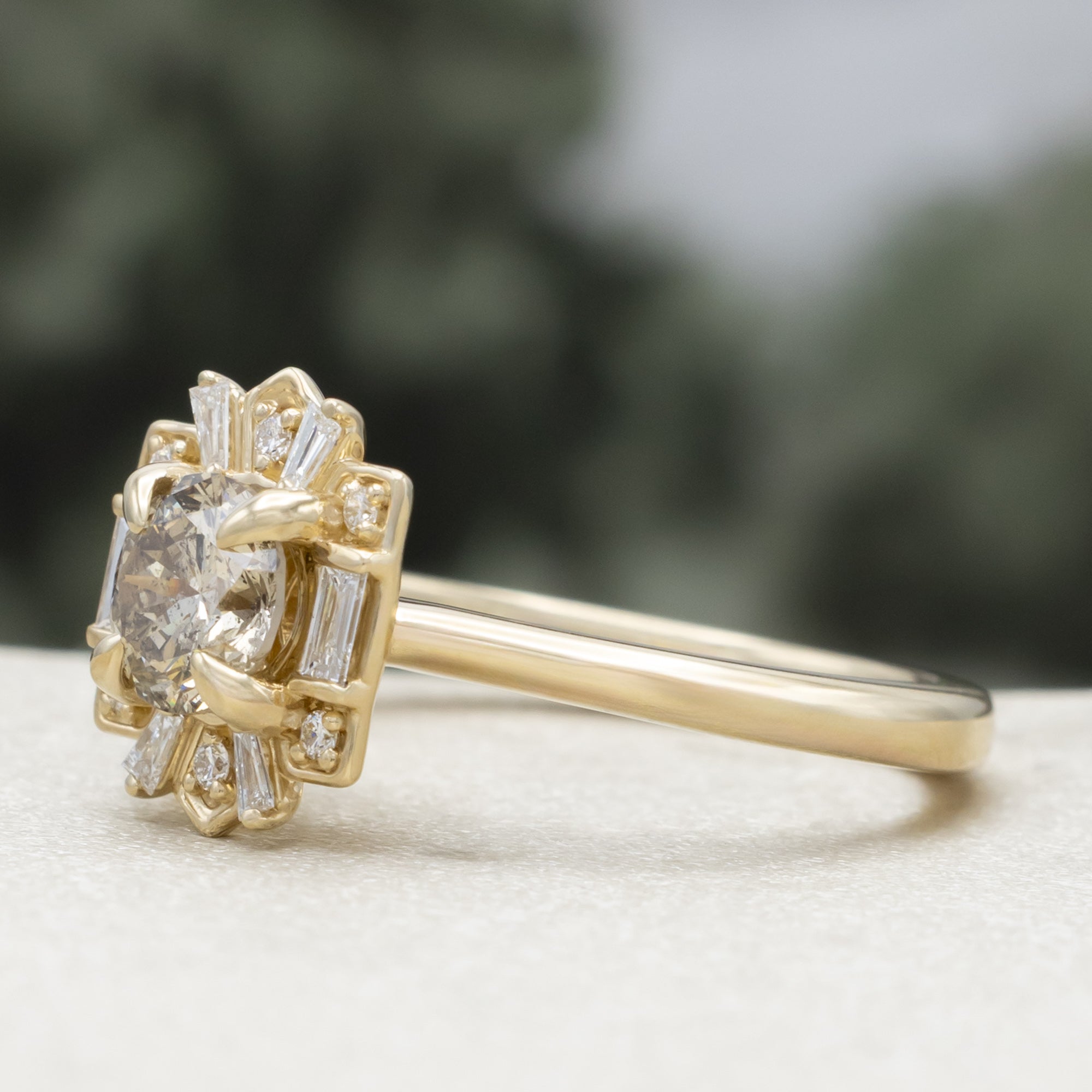 Gold ring with a champagne diamond center stone against a blurred green background