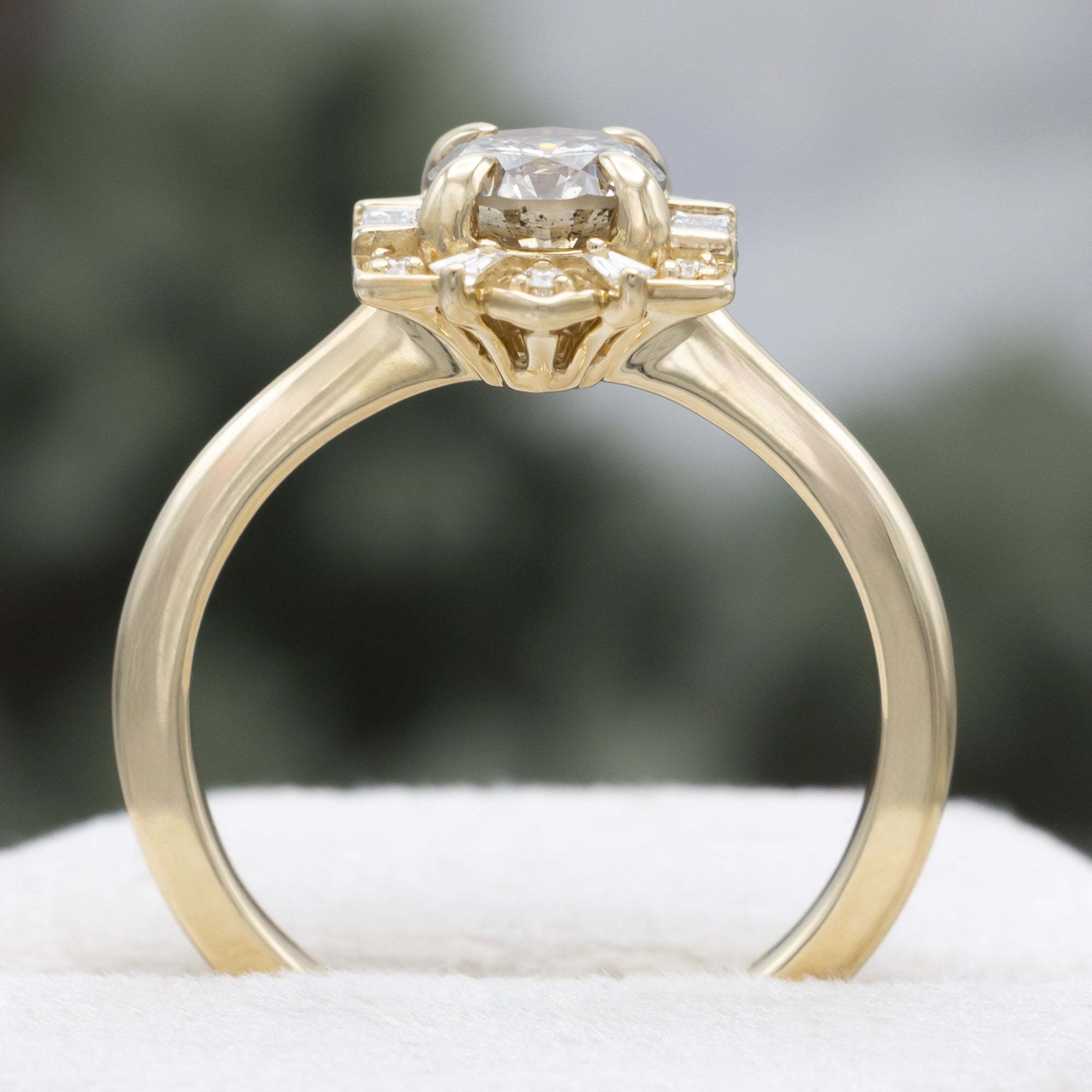 Gold ring with a champagne diamond center stone against a blurred green background