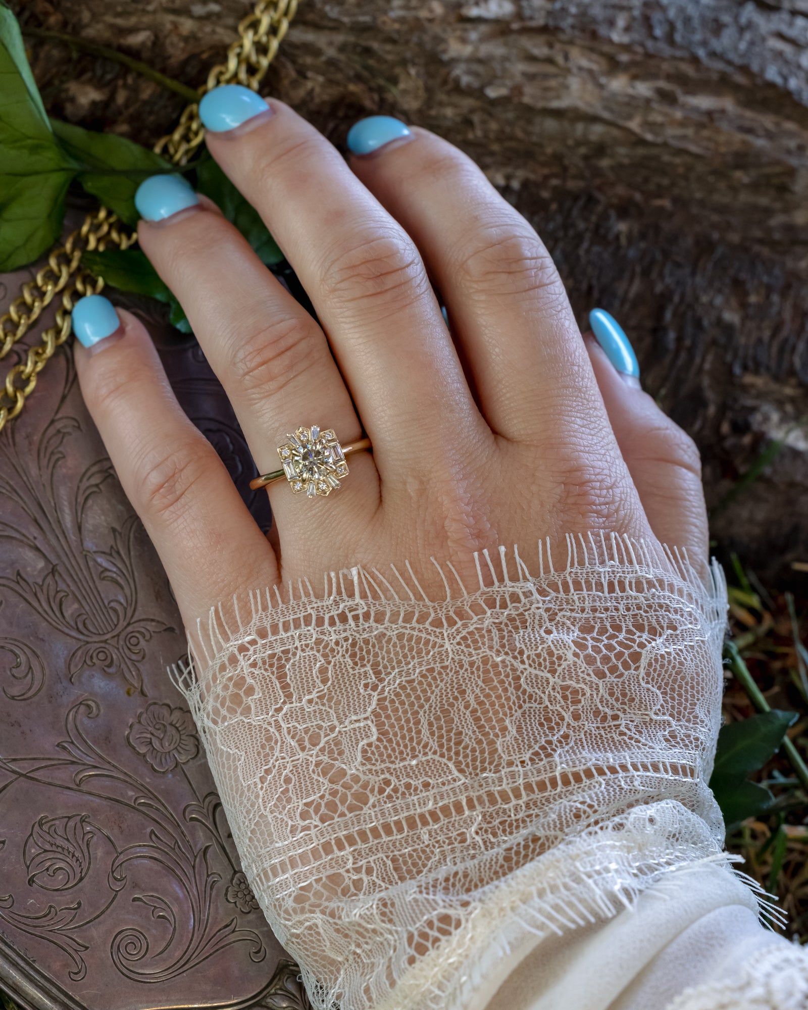 Hand wearing gold ring with champagne diamond against natural elements