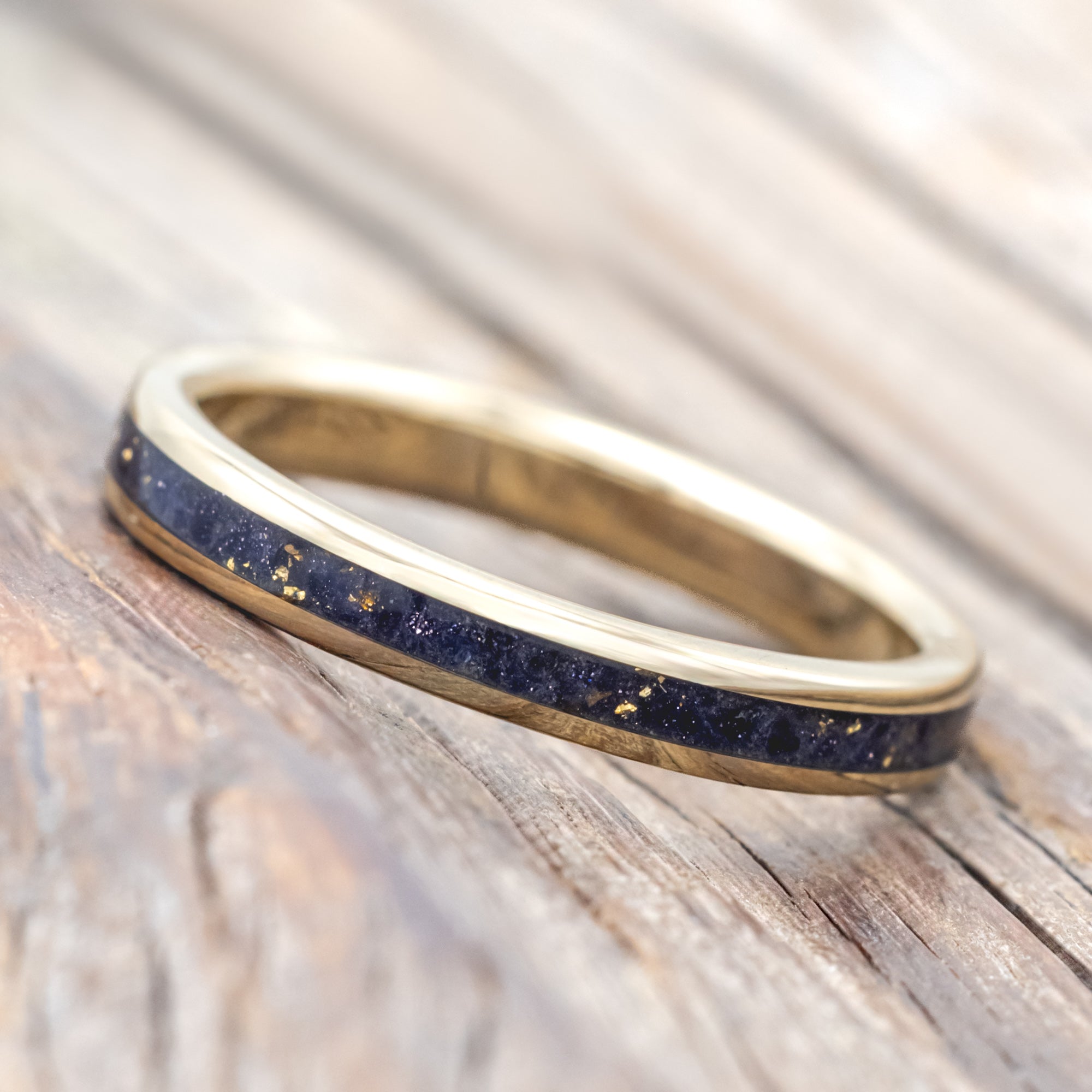 Gold ring with blue goldstone and gold leaf inlay on a wooden surface