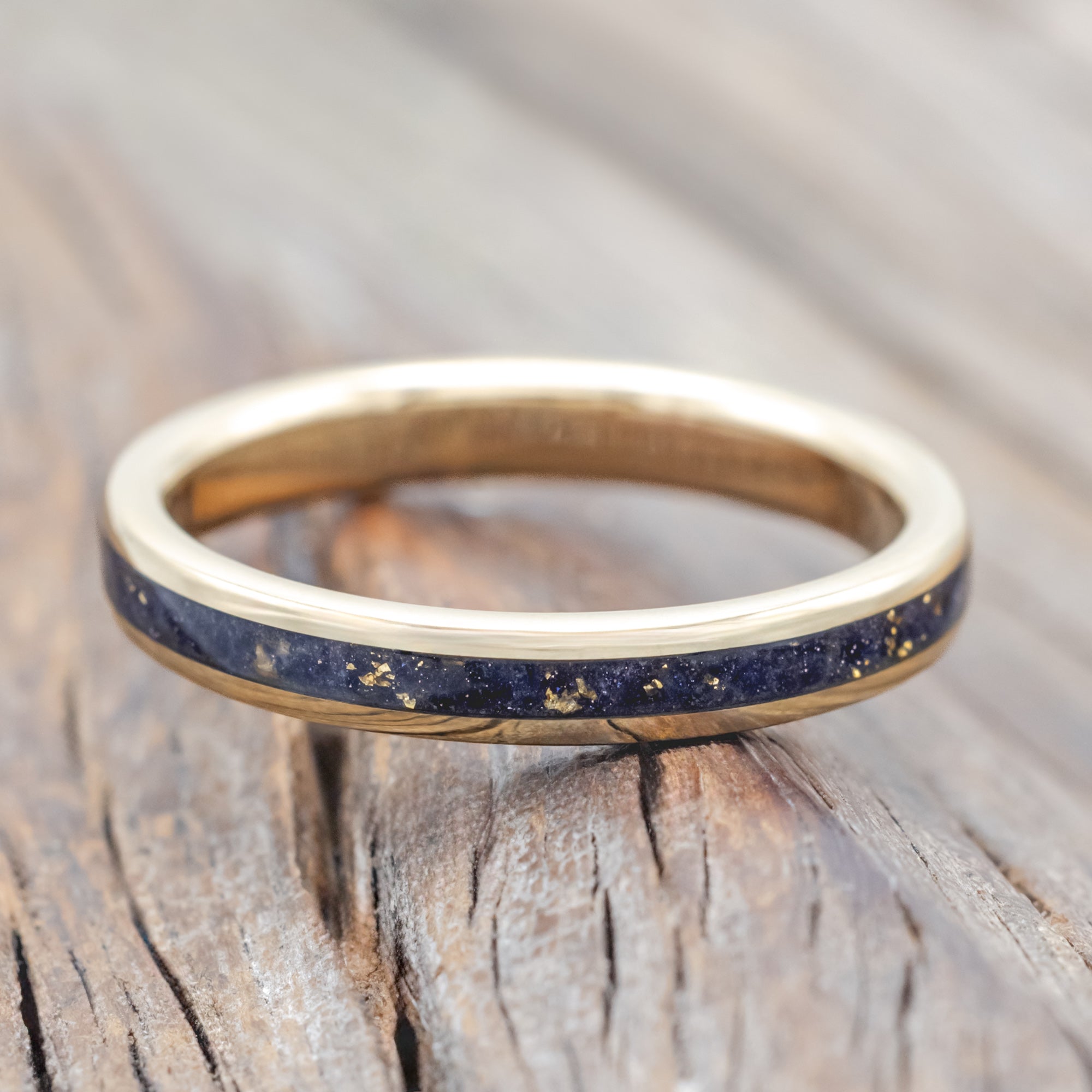 Gold ring with blue goldstone and gold leaf inlay on a wooden surface