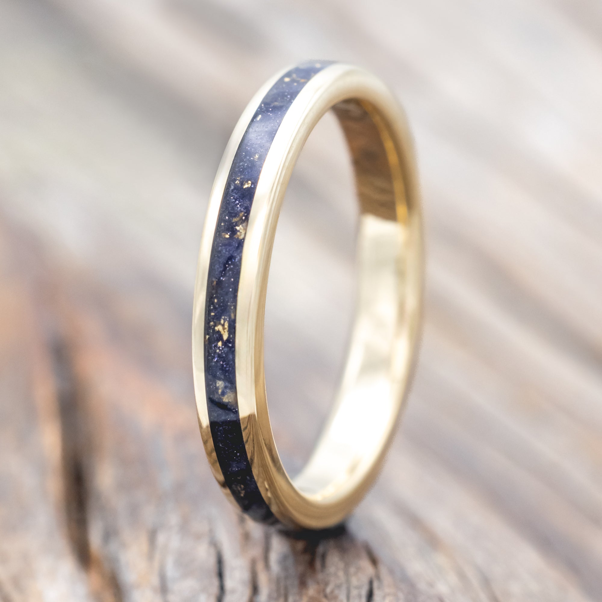 Gold ring with blue goldstone and gold leaf inlay on a wooden surface