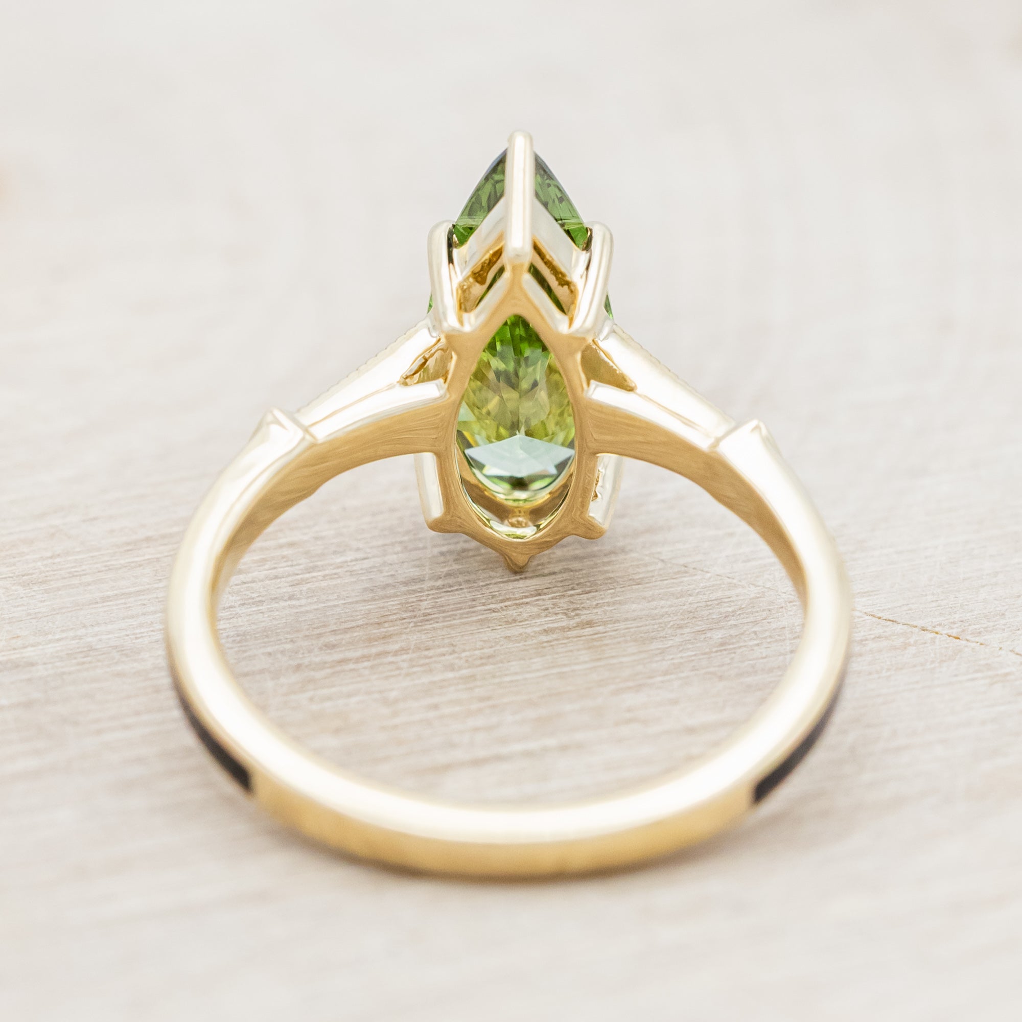 14K yellow gold ring with a green diamond on a neutral background
